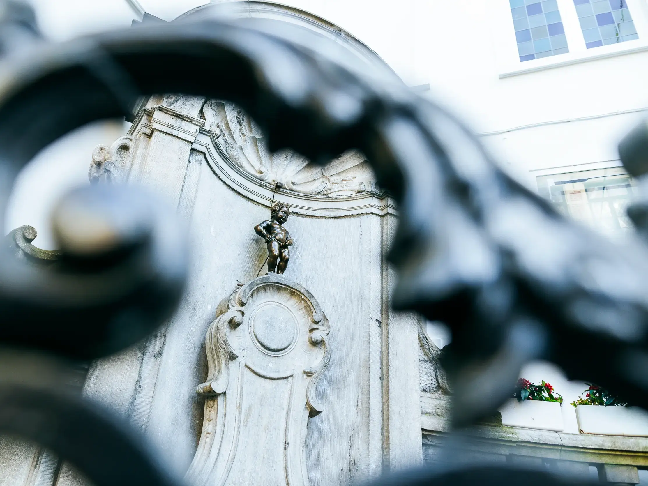 Künstlerischer Blick durch einen Zaun auf die berühmte Brunnenfigur Manneken Pis, das Wahrzeichen von Brüssel.