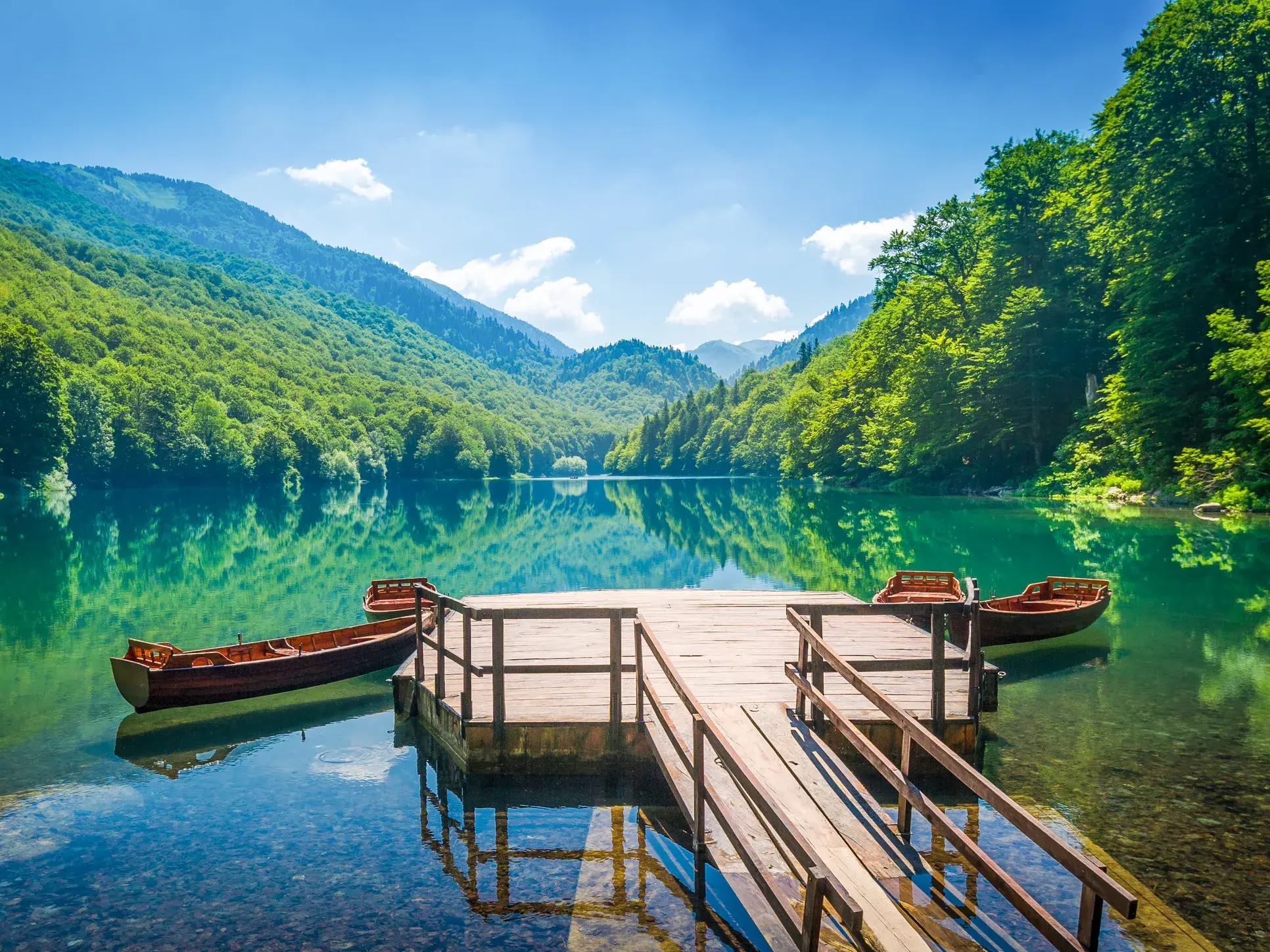 Hölzerner Steg mit zwei Ruderbooten auf dem klaren Biogradsko Jezero im Nationalpark Biogradska Gora in Montenegro.