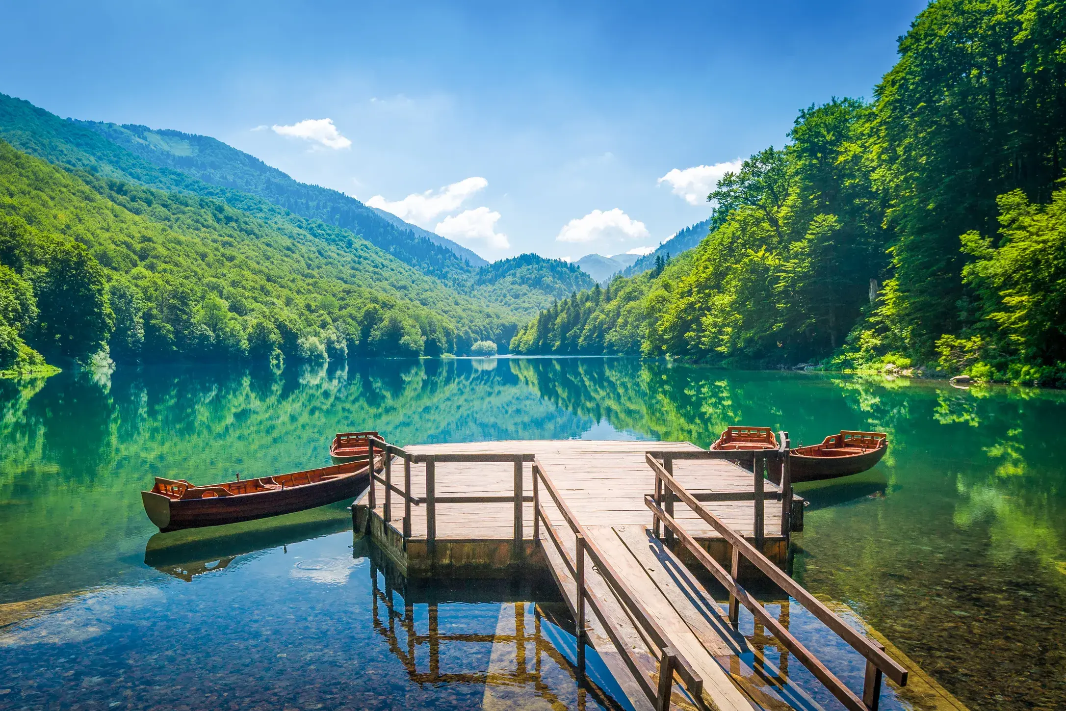 Hölzerner Steg mit zwei Ruderbooten auf dem klaren Biogradsko Jezero im Nationalpark Biogradska Gora in Montenegro.