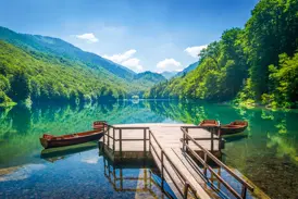 Hölzerner Steg mit zwei Ruderbooten auf dem klaren Biogradsko Jezero im Nationalpark Biogradska Gora in Montenegro.
