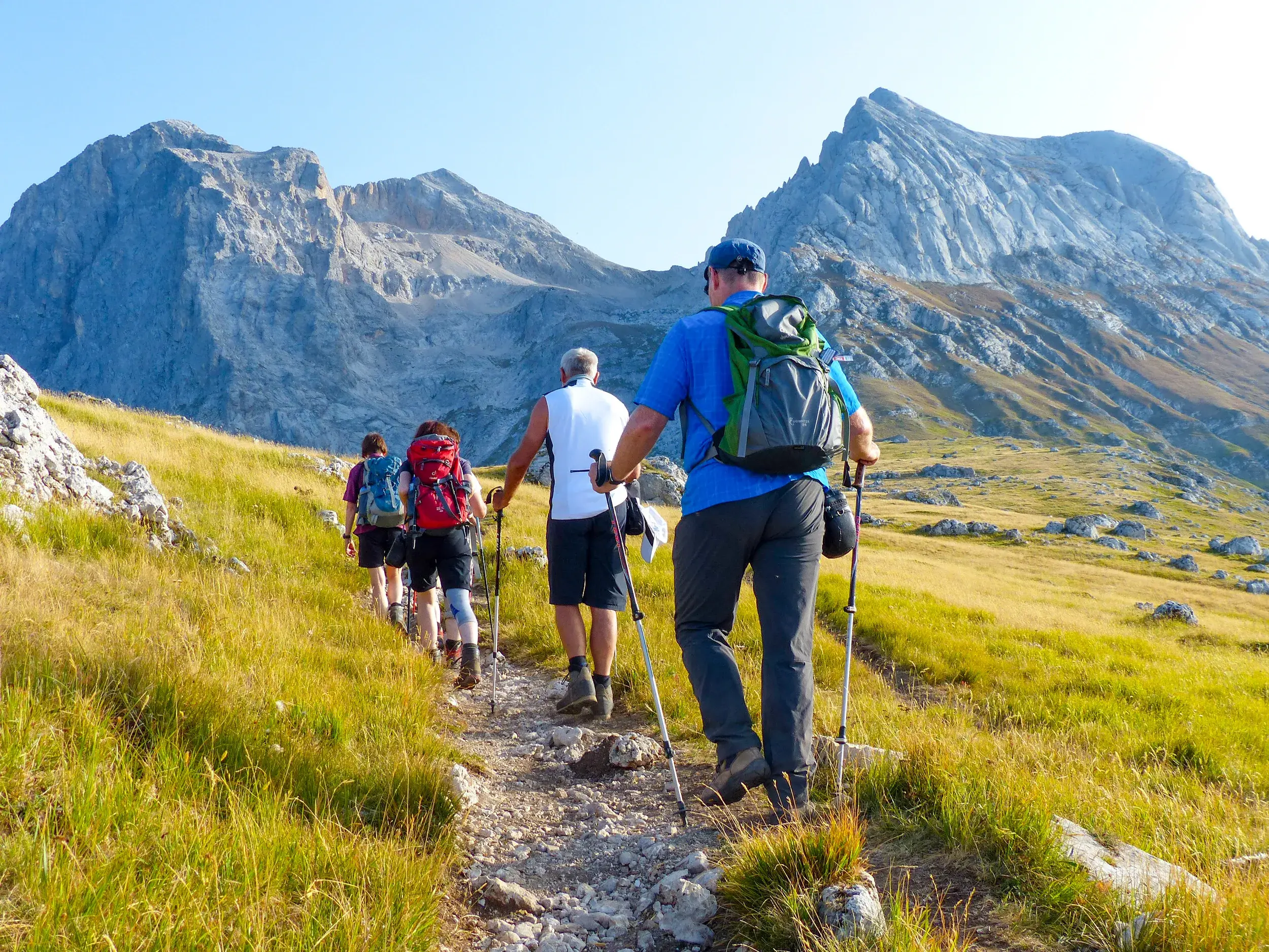 Reisegruppe beim Trekking auf einem Bergpfad mit Blick auf die Felsmassive des Gran Sasso d'Italia in den Abruzzen.