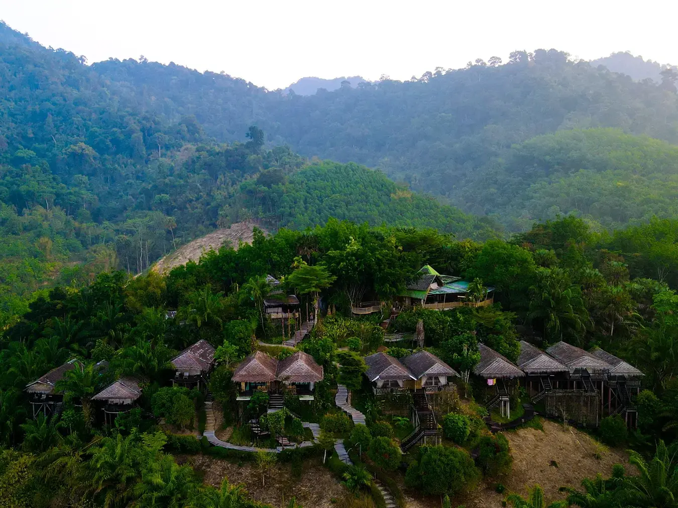 Luftaufnahme des Boutique Camps mit seinen komfortablen Hütten an einem Hang im dichten Regenwald des Khao-Sok-Nationalparks.