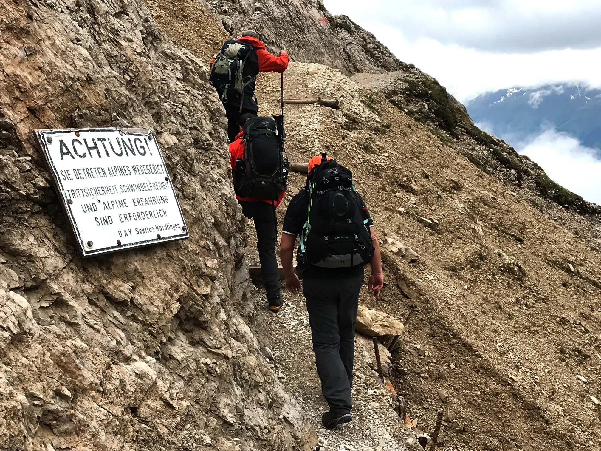 Eine Wandergruppe auf einem schmalen, ausgesetzten Geröllpfad im Karwendelgebirge auf dem Weg zur Eppzirler Scharte.