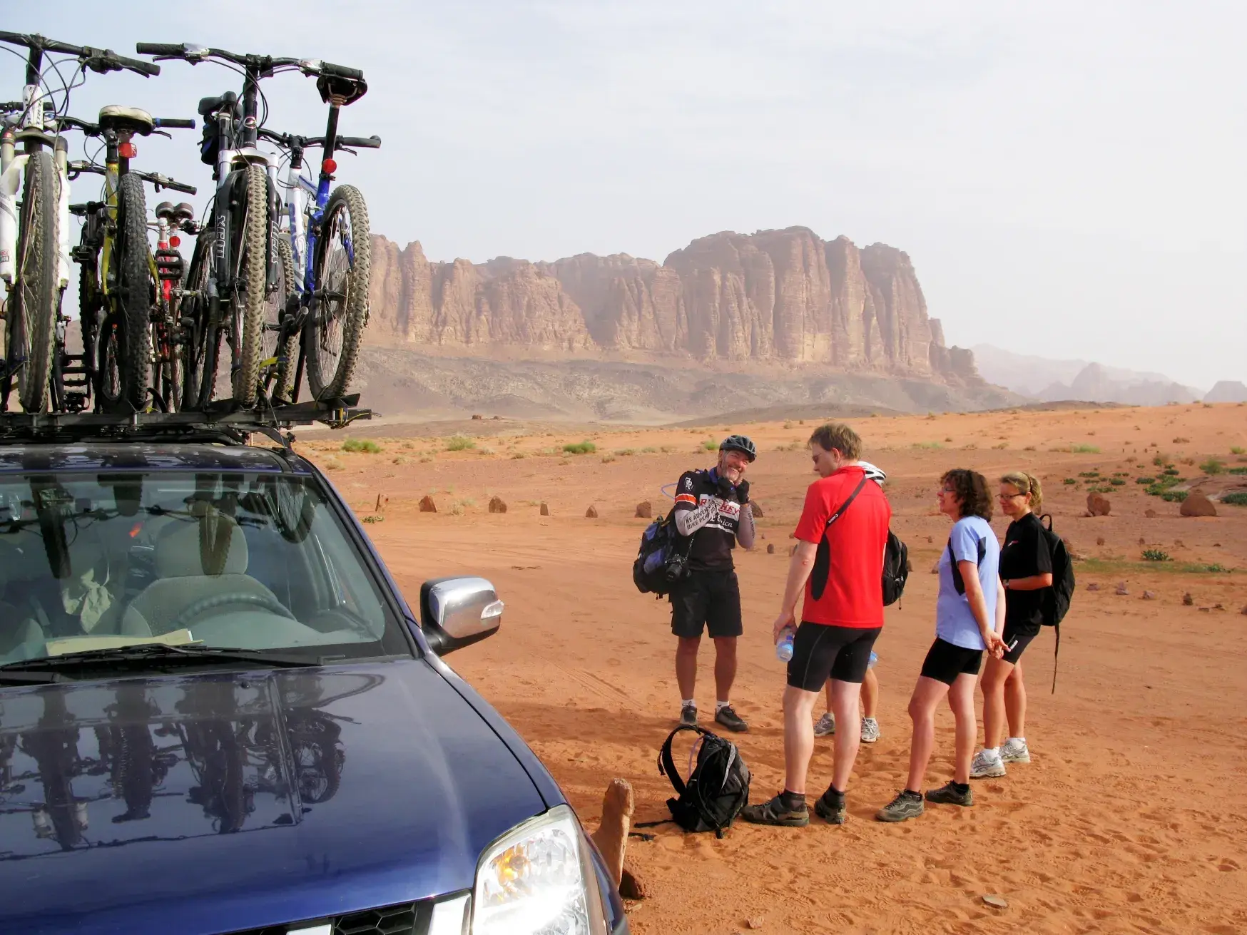 Eine kleine Gruppe Radfahrer macht bei ihrer geführten Rundreise eine Pause in der Wüstenlandschaft von Wadi Rum, Jordanien.