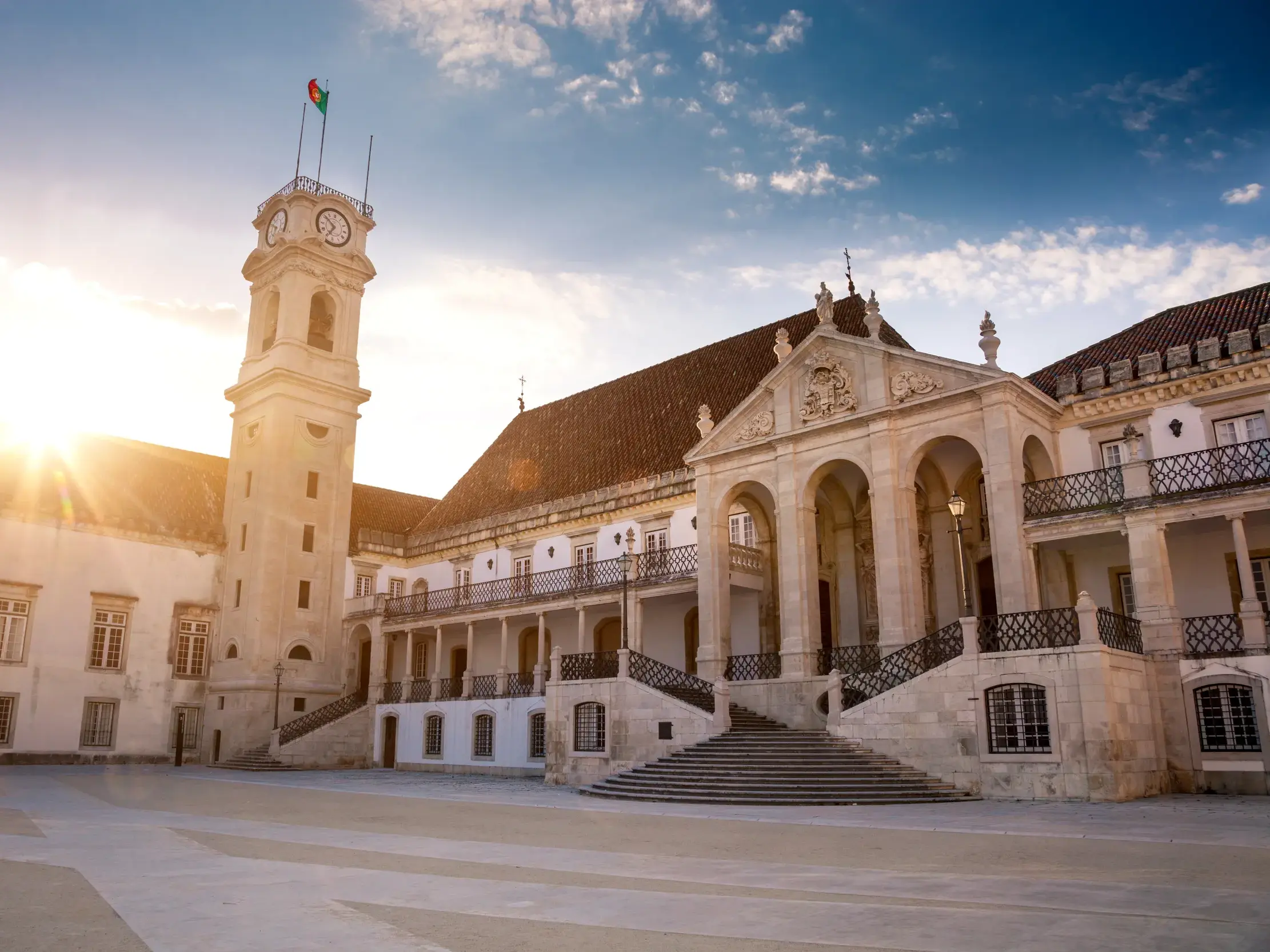 Der historische Innenhof im Universitätsviertel von Coimbra mit dem markanten Uhrenturm bei Sonnenuntergang.