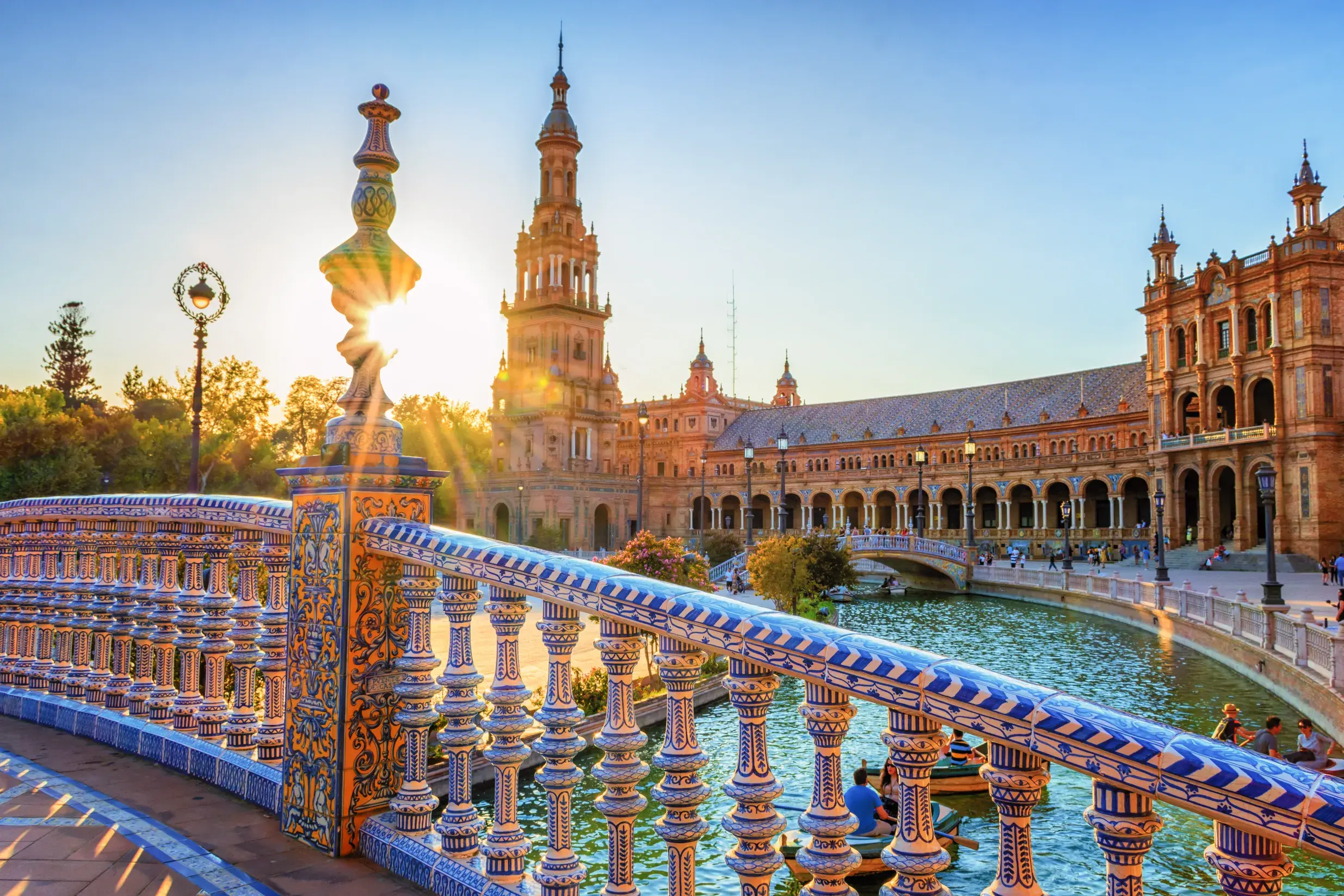 Prachtvolle Keramikbrücke an der Plaza de España in Sevilla mit Blick auf den Kanal und die Arkaden im goldenen Abendlicht.