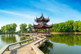 Eine Steinbrücke führt zu einem traditionellen Pavillon auf einem See im kunstvollen Garten des Meisters der Netze in Suzhou.