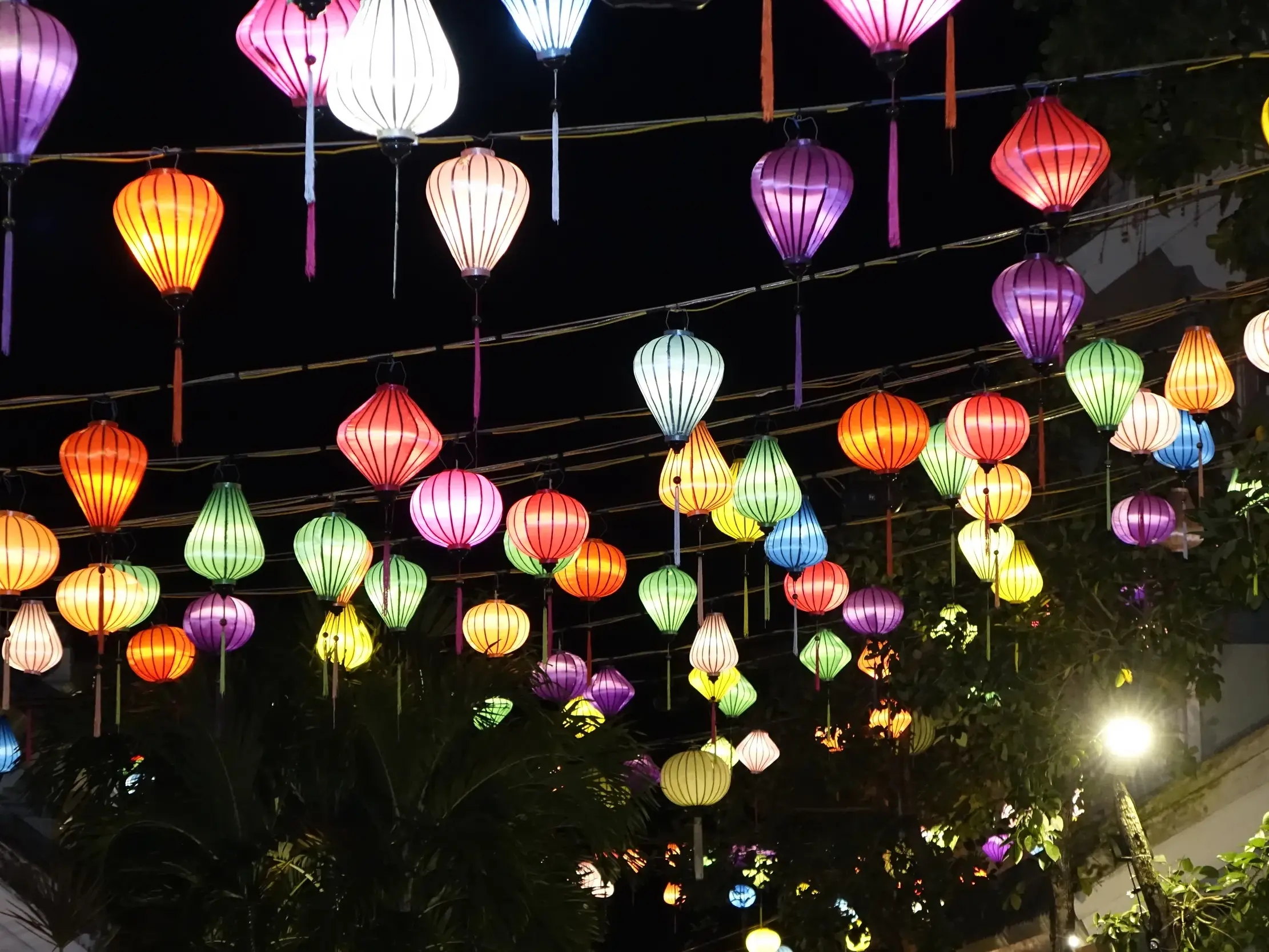 Zahlreiche bunte Seidenlampions erleuchten bei Nacht eine Gasse in der historischen Altstadt von Hoi An, Vietnam.