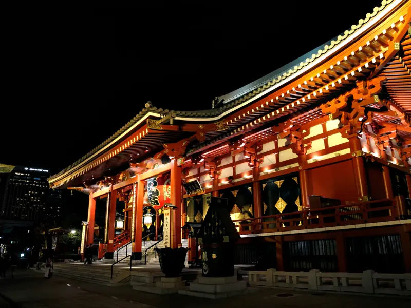 Der historische Asakusa-Kannon-Tempel in Tokio, nachts eindrucksvoll in warmen Rottönen beleuchtet.