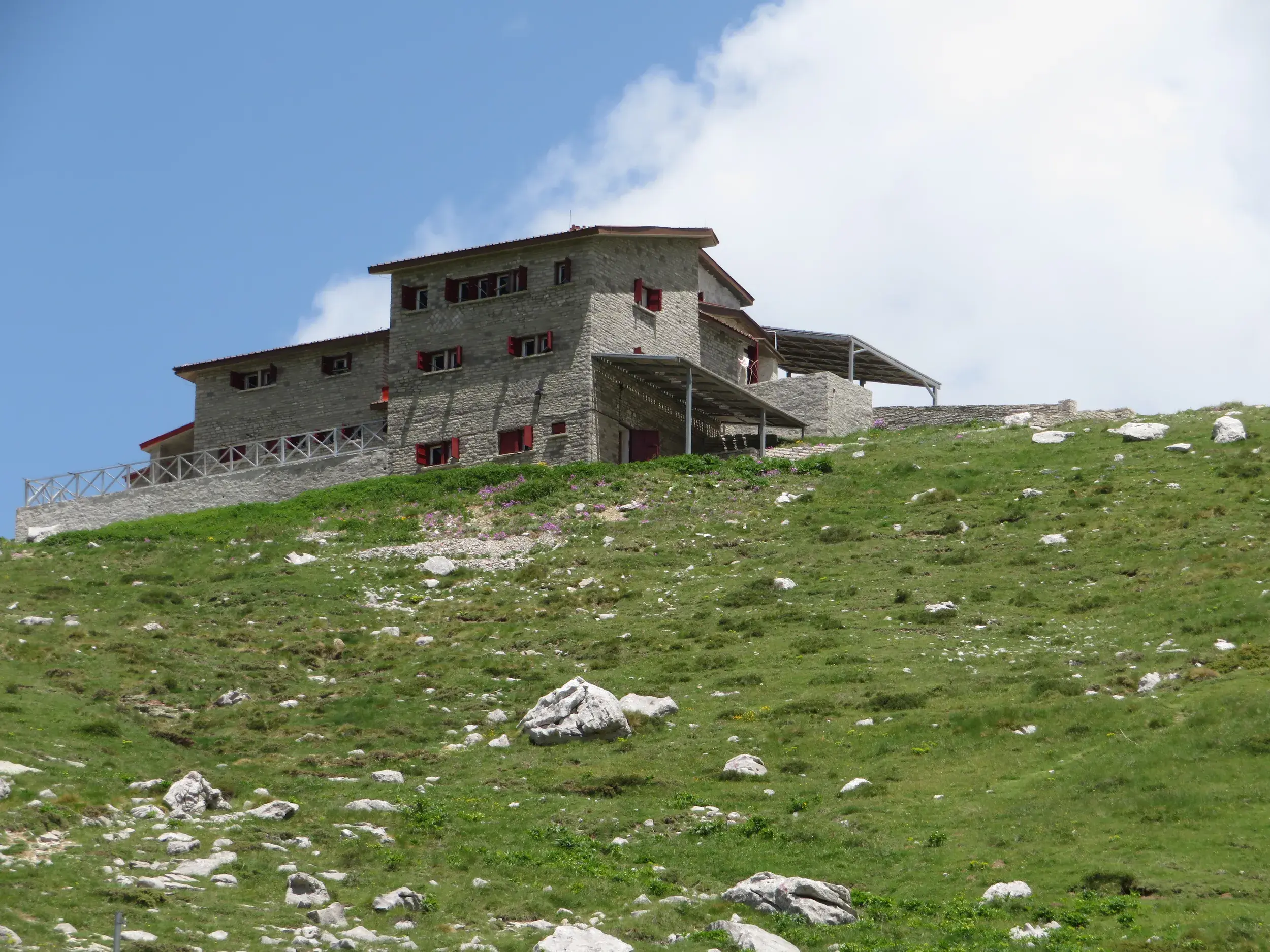 Die steinerne Astrakas-Berghütte in der Zagori-Region steht auf einem grünen Almhang und dient als Unterkunft beim Trekking.