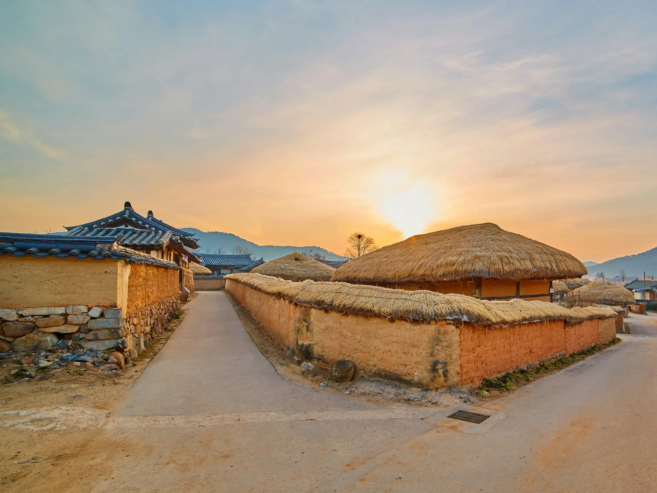 Sonnenuntergang über dem UNESCO-Weltkulturerbe Hahoe-Dorf in Andong mit traditionellen Häusern mit Stroh- und Ziegeldächern.