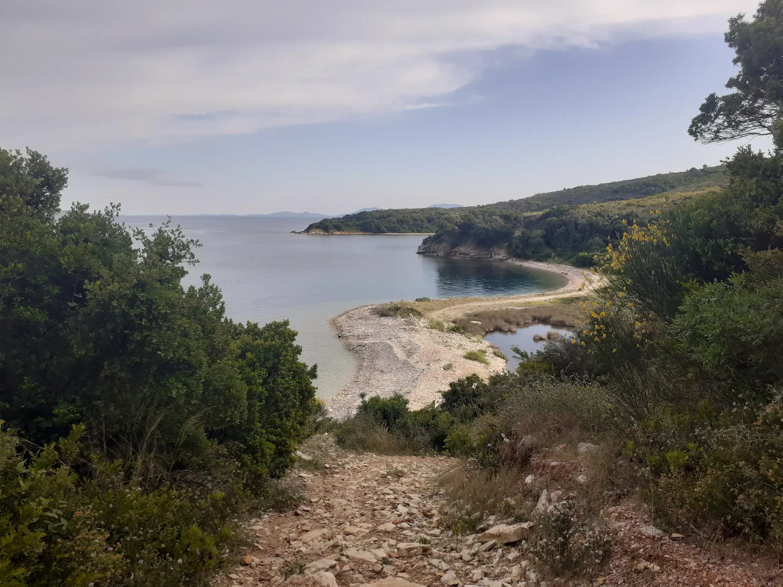 Ein steiniger Küstenpfad führt zu einer einsamen Bucht mit Lagune im Naturschutzgebiet der Erimitis-Halbinsel auf Korfu.