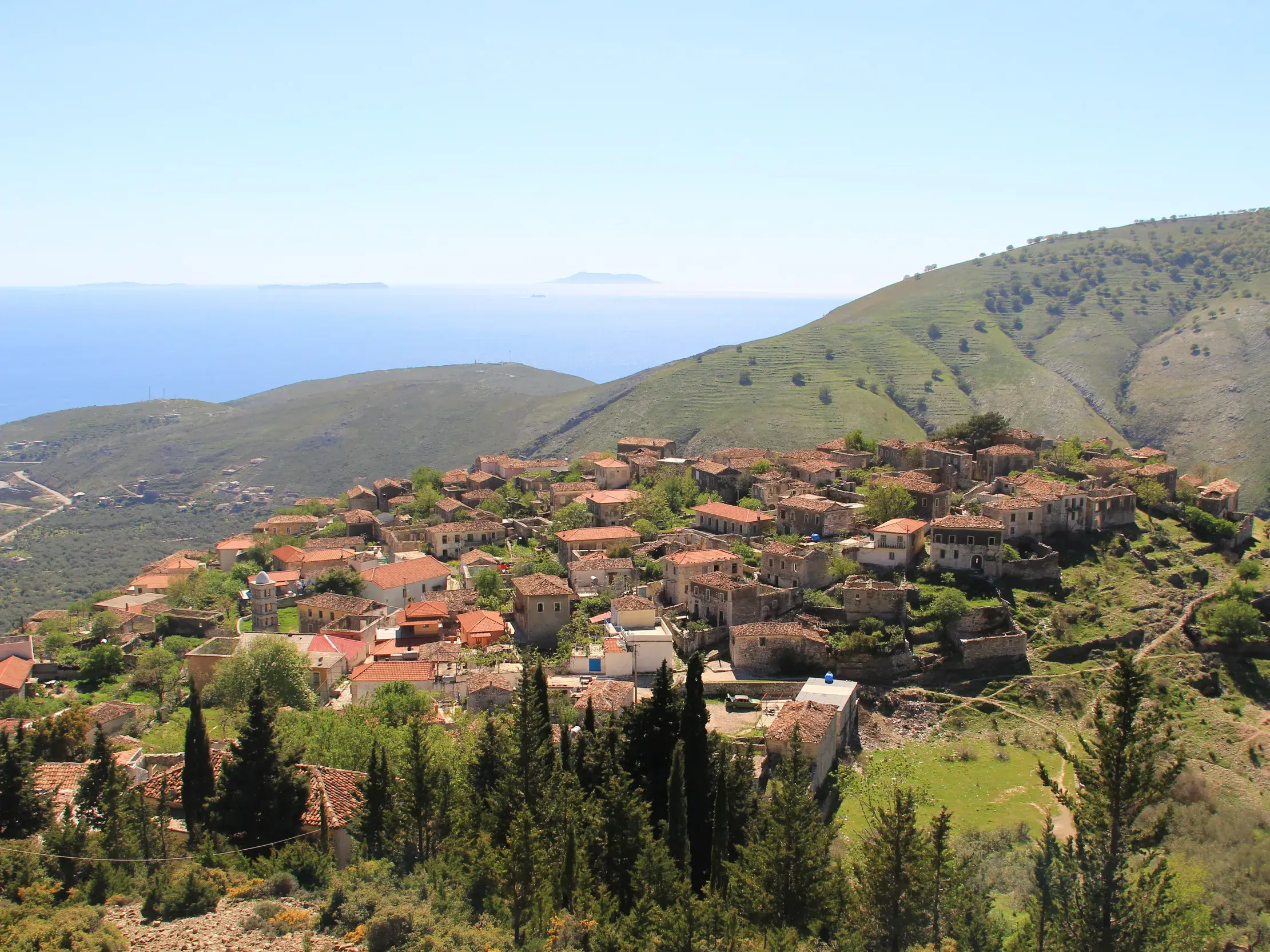 Panoramablick beim Wandern auf das historische Dorf Qeparo an der Küste Albaniens mit Blick auf das tiefblaue Ionische Meer.