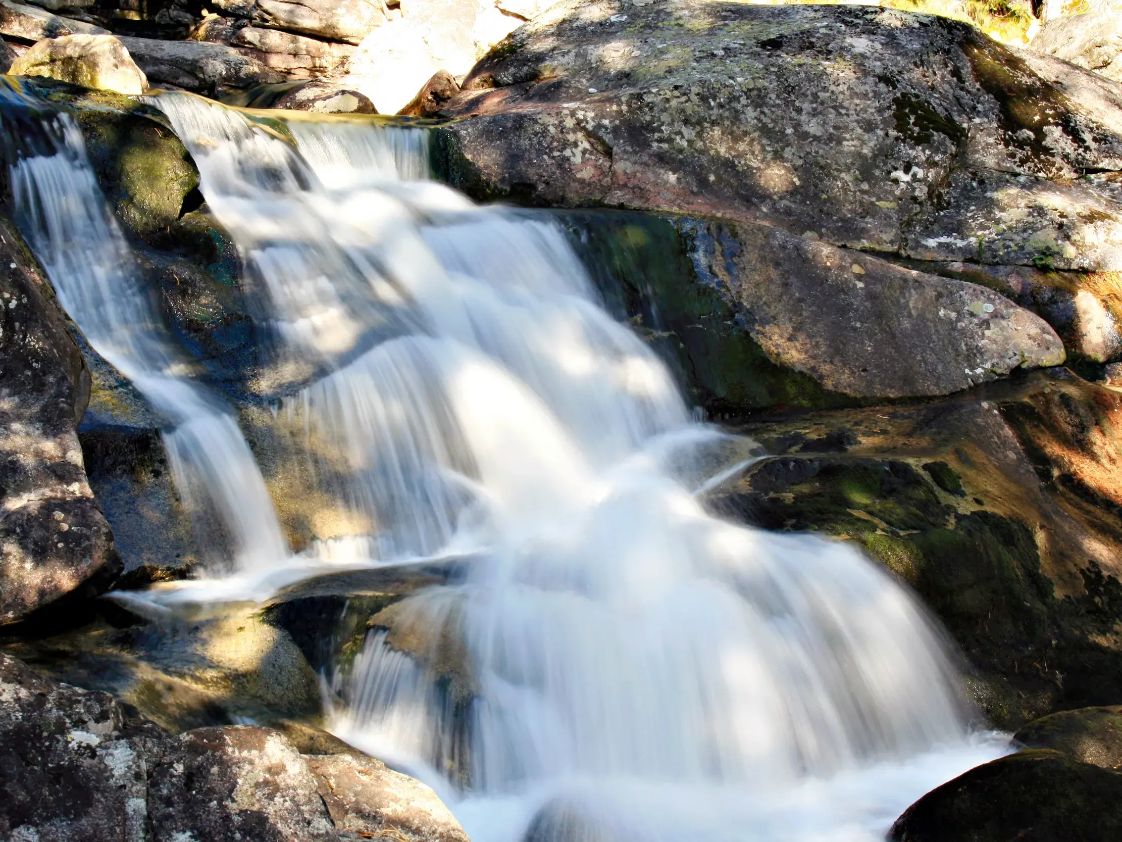 Kühle Kaskaden der Wasserfälle des Studený Potok fließen bei einer Wanderung in der Hohen Tatra über bemooste Felsen.