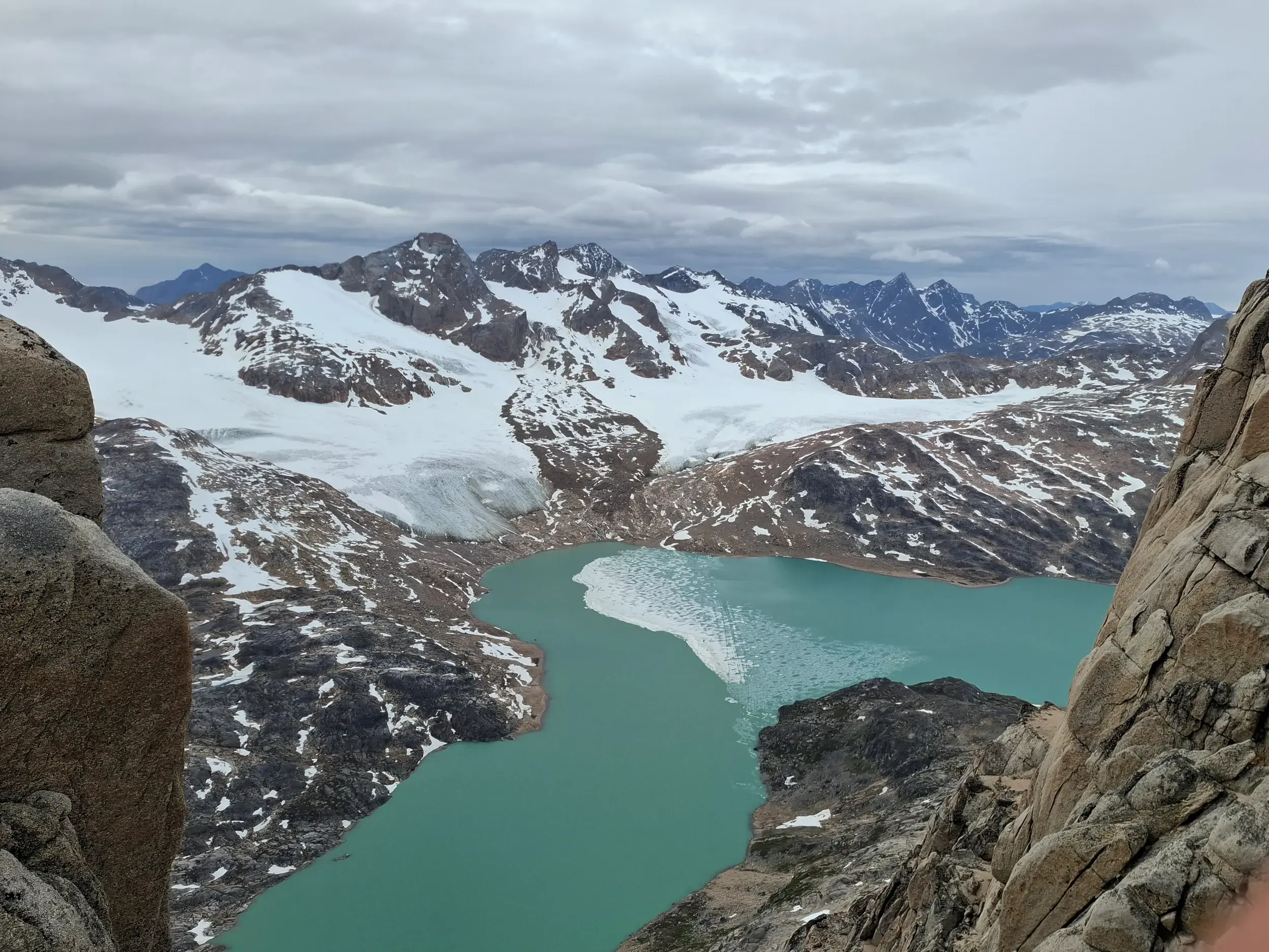 Spektakulärer Ausblick beim Trekking auf den türkisen Sangmileq-Fjord, umgeben von Gletschern in der arktischen Bergwelt Ostgrönlands.