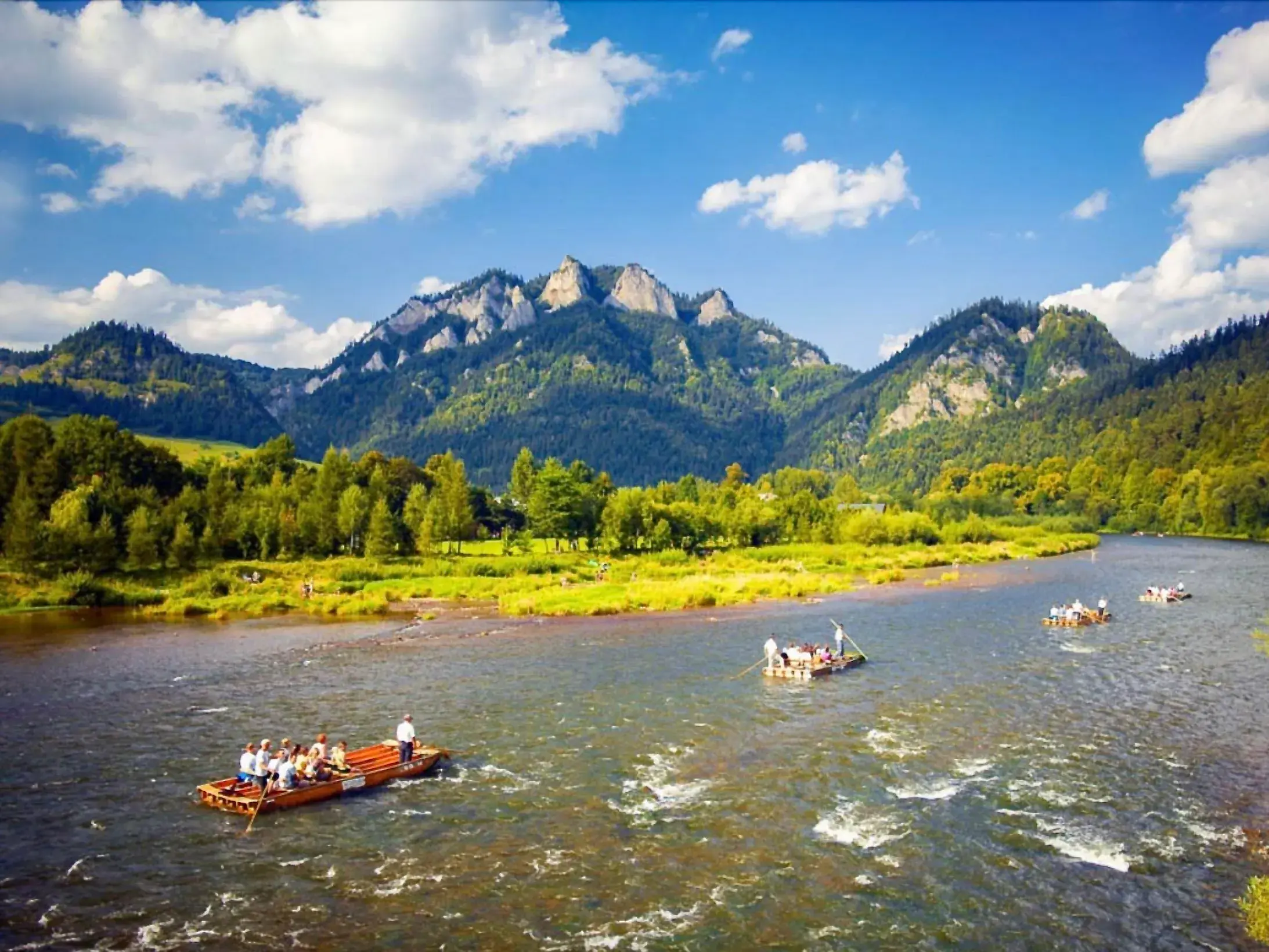 Traditionelle Flöße mit Reisenden auf dem Dunajec vor der Bergkulisse des Trzy Korony im Pieniny-Nationalpark.