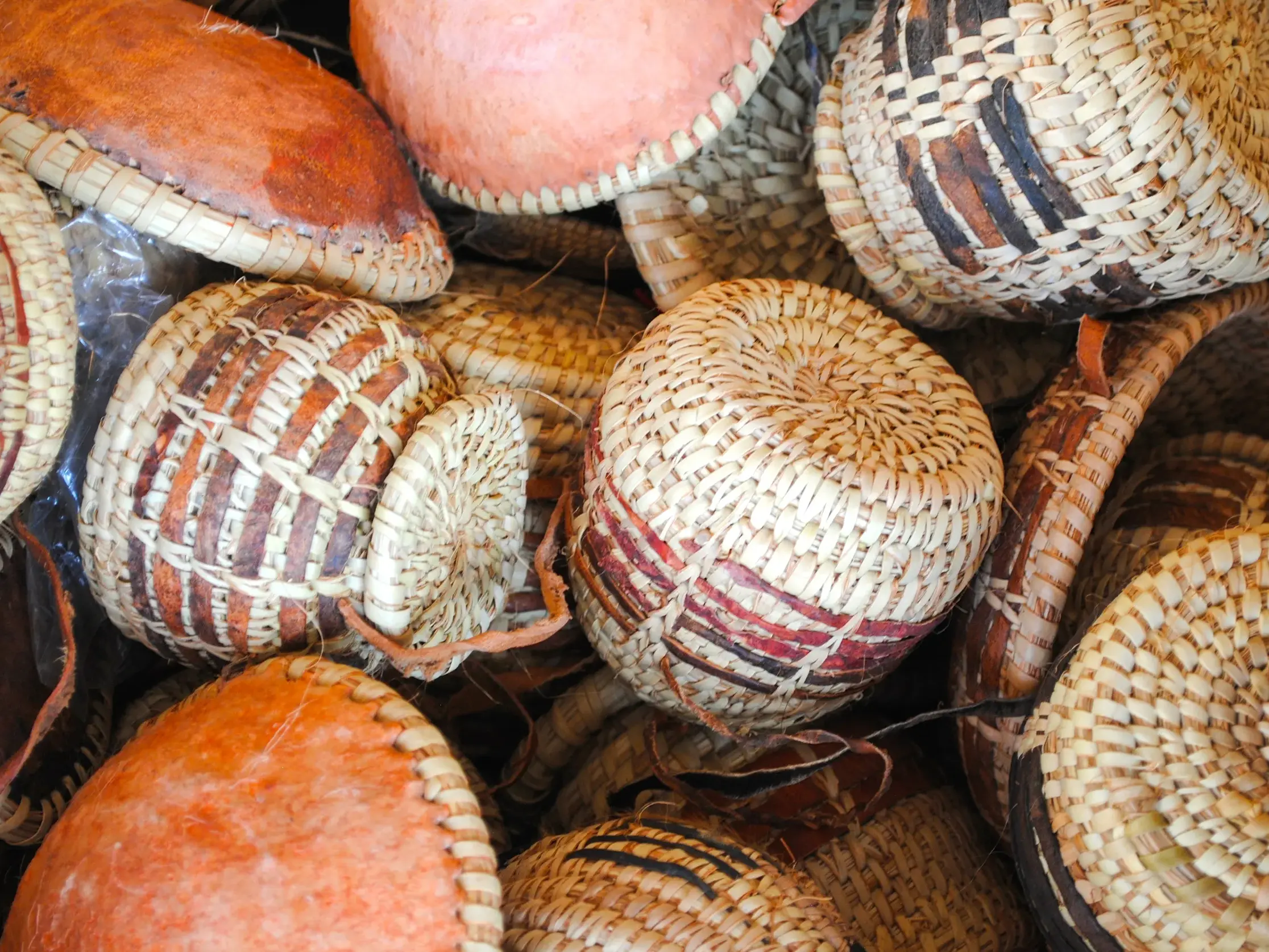 Nahaufnahme von traditionellem, omanischem Kunsthandwerk: handgeflochtene Körbe mit bunten Mustern auf einem Souk in Nizwa.
