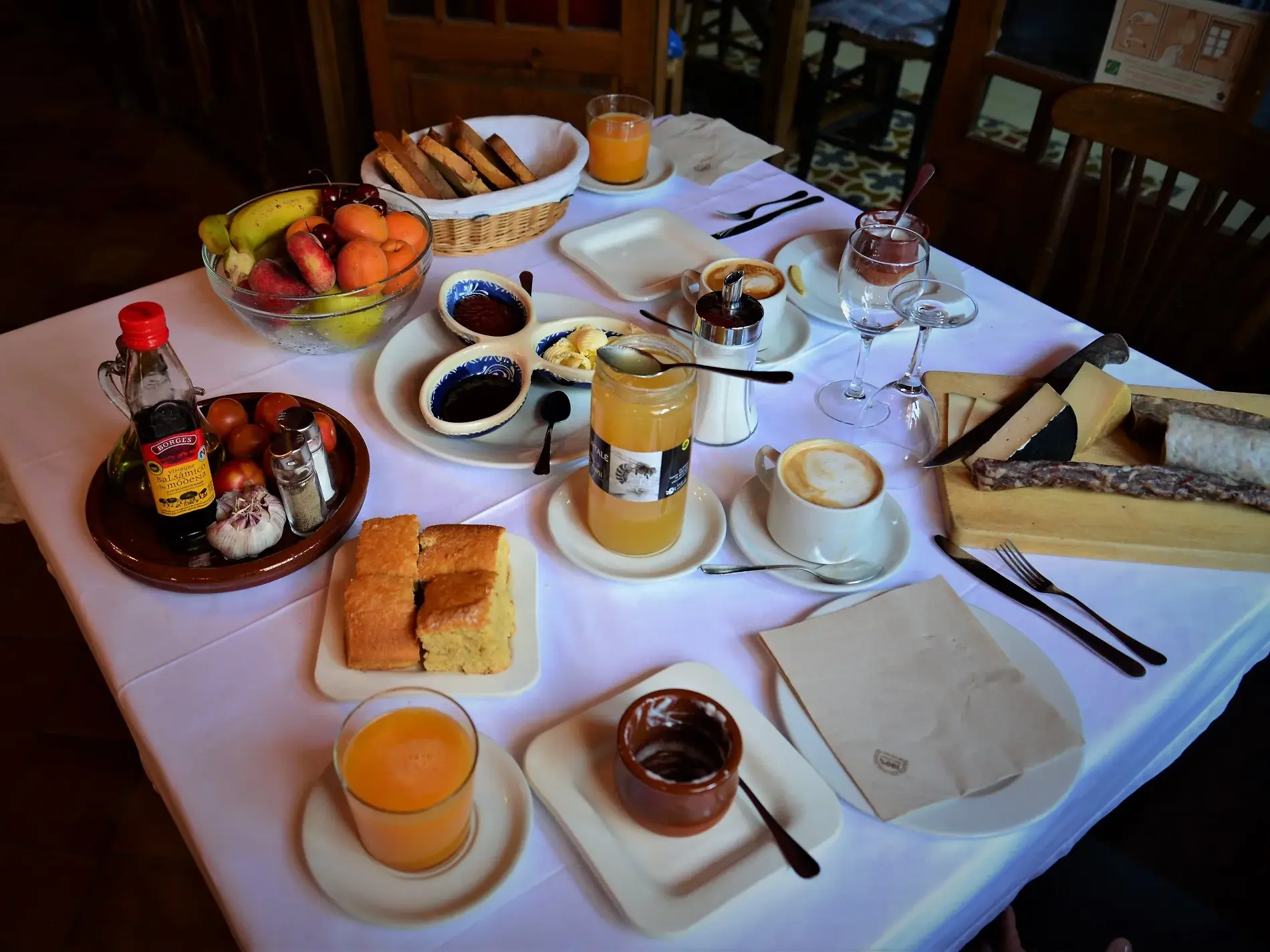 Rustikaler Frühstückstisch bei einer Gastfamilie in den Pyrenäen, gedeckt mit Obst, Gebäck, Käse und Kaffee.