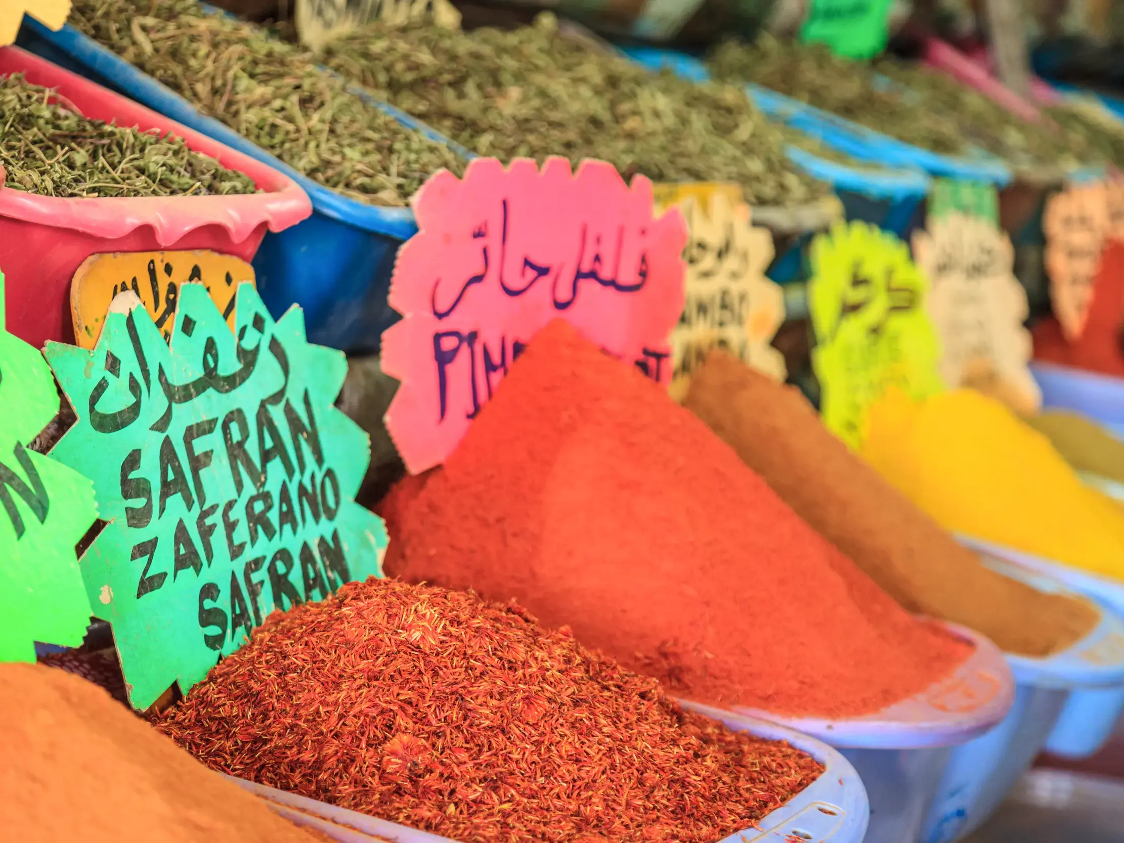 Bunte Gewürzberge wie Safran und Chili in Schalen auf einem traditionellen Souk in Tunesien