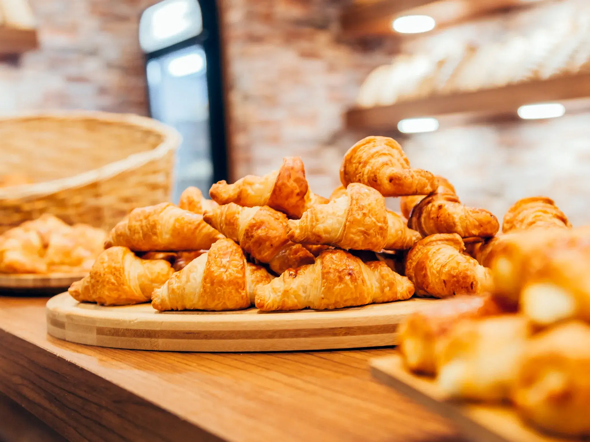 Goldbraune Croissants auf einem Holzbrett in einer Pariser Bäckerei, ein Genuss der französischen Küche auf einer Städtereise.