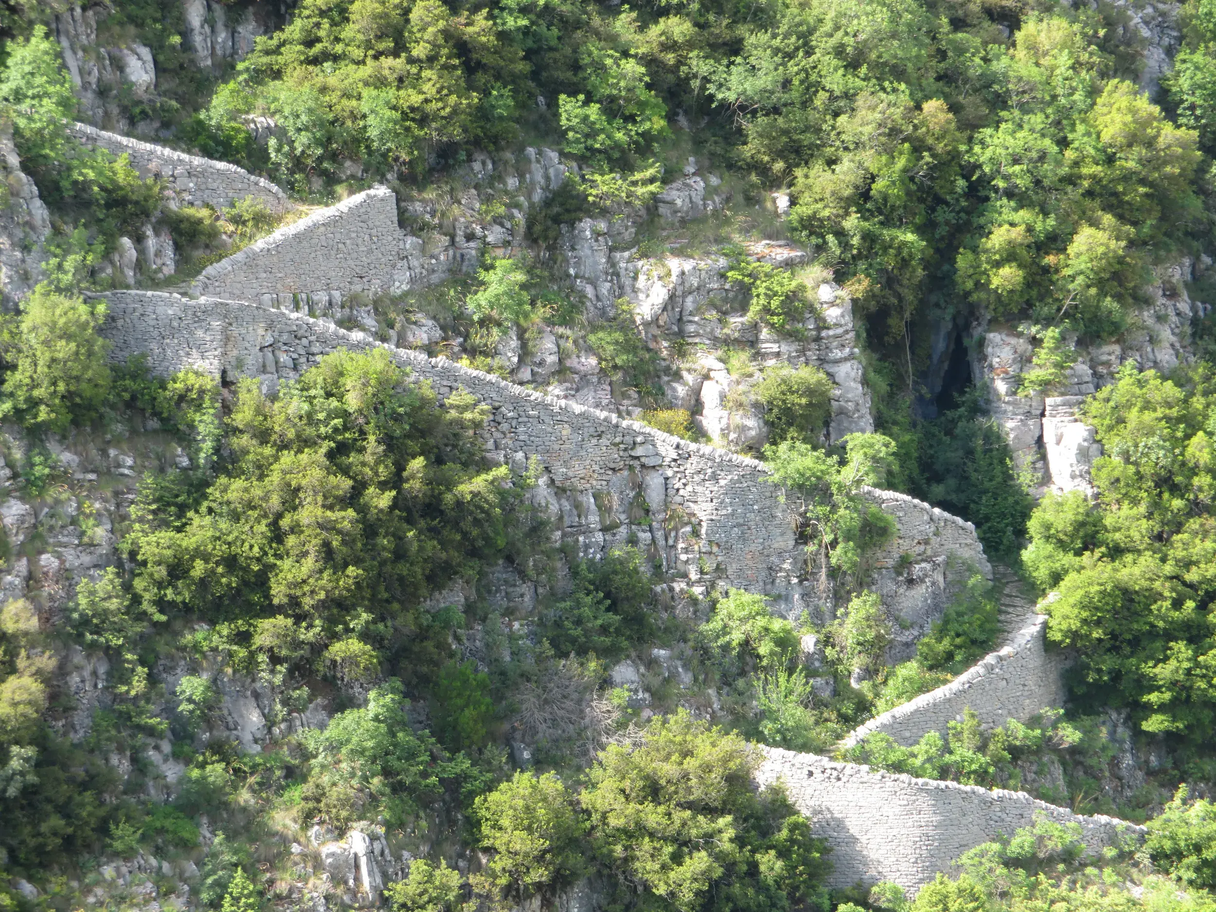 Die historischen Steintreppen von Vradeto schlängeln sich durch die grüne Berglandschaft der Zagori-Region in Griechenland.