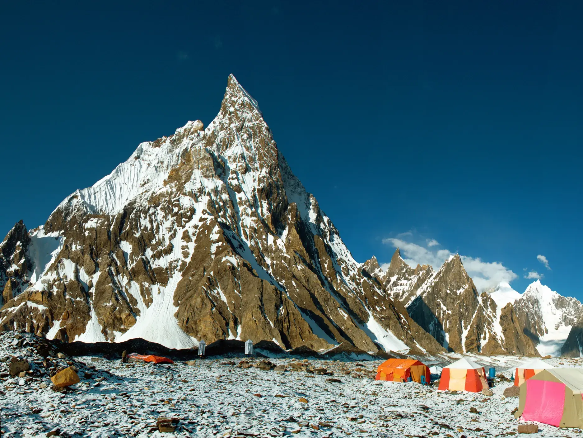 Farbenfrohe Zelte einer Trekking-Gruppe auf dem Weg zum Gondogoro-Pass vor dem schneebedeckten Laila Peak im Karakorum.