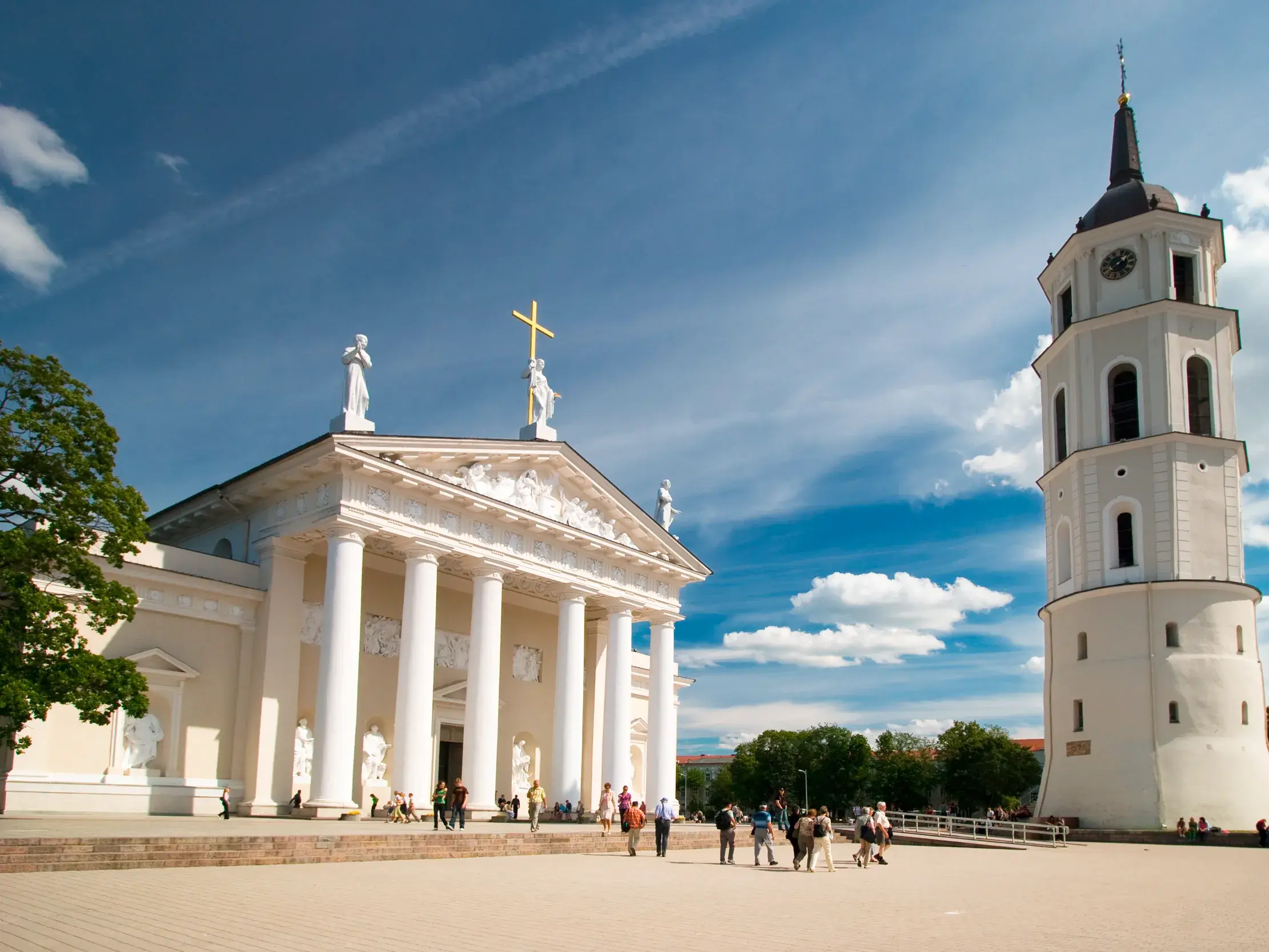 Eine Reisegruppe besichtigt die klassizistische Kathedrale von Vilnius mit ihrem Glockenturm auf dem sonnigen Kathedralenplatz.
