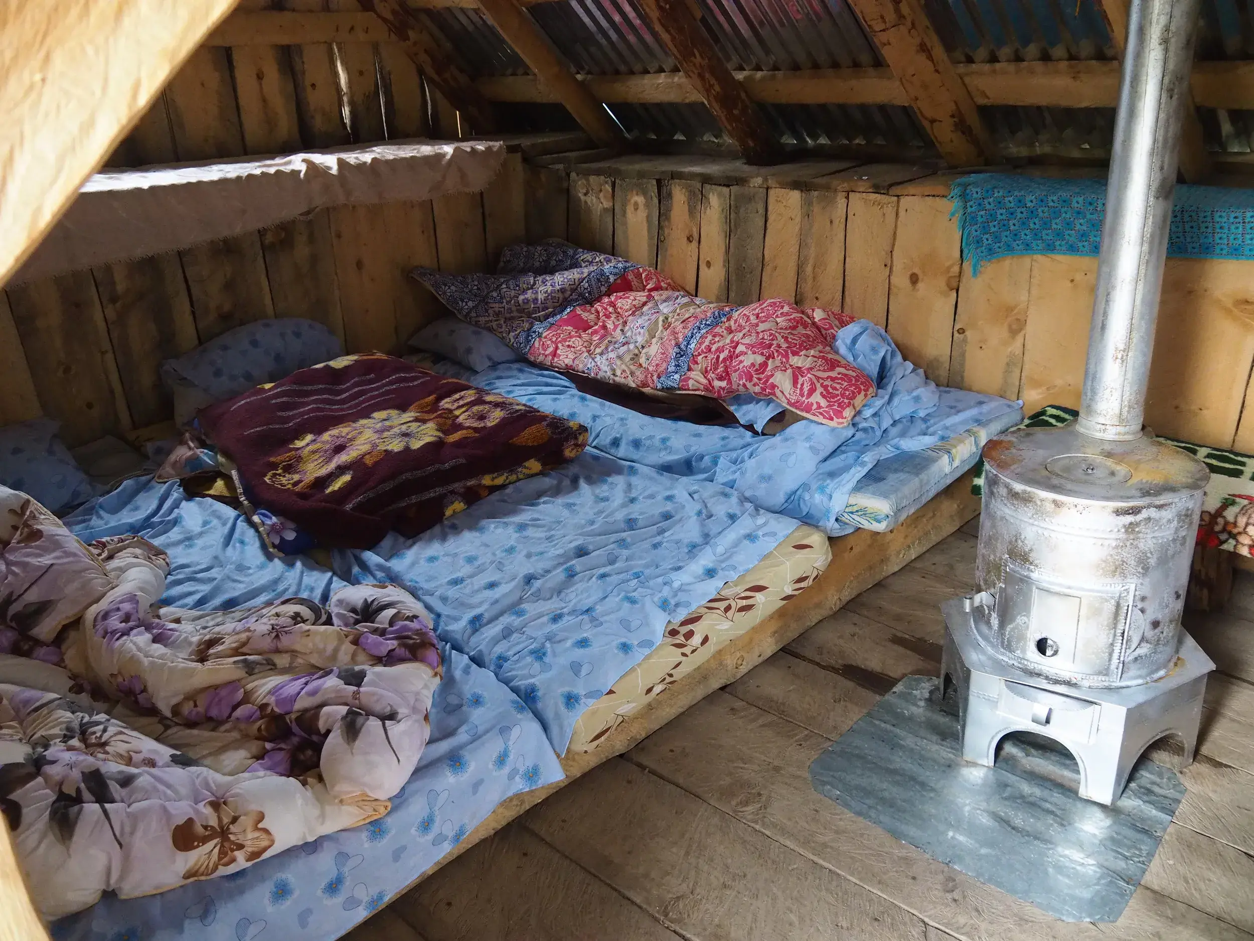 Rustikales Mehrbettzimmer in einer einfachen Berghütte mit Holzofen auf der Trekkingreise 'Peaks of the Balkans'.
