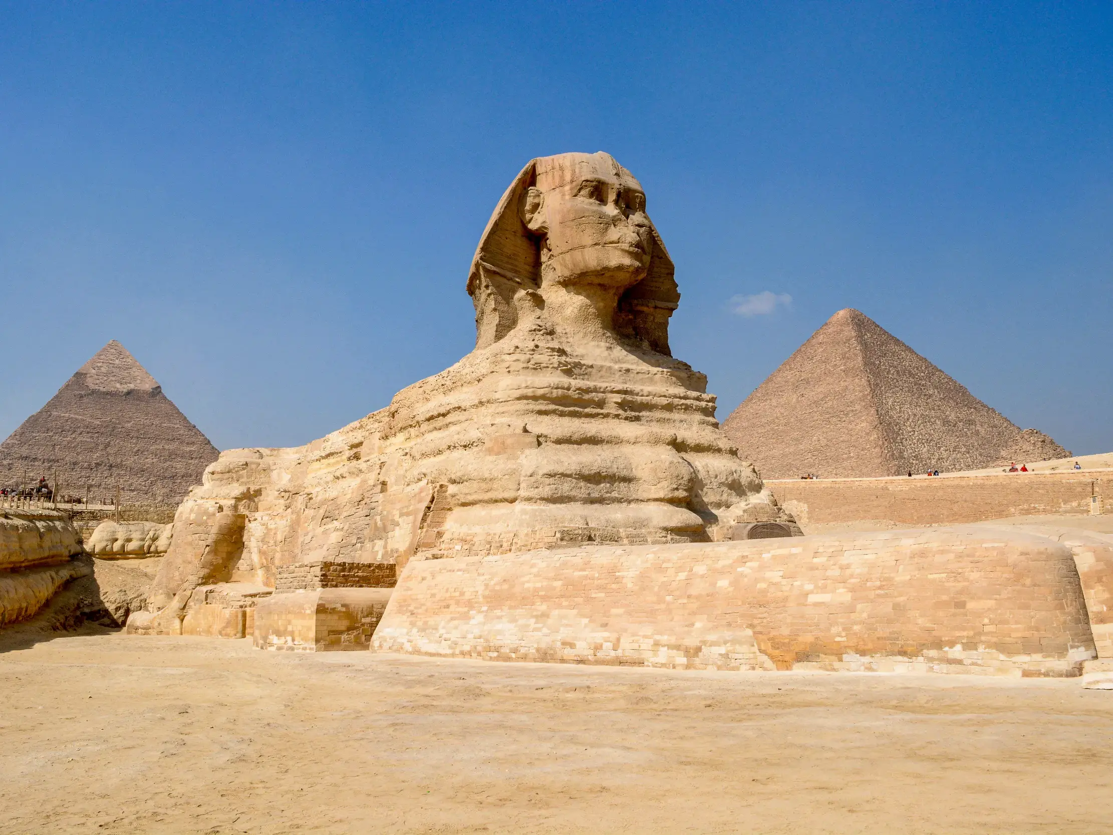 Die beeindruckende Große Sphinx von Gizeh thront vor den Pyramiden in der Wüste Ägyptens unter strahlend blauem Himmel.