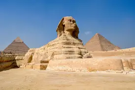 Die beeindruckende Große Sphinx von Gizeh thront vor den Pyramiden in der Wüste Ägyptens unter strahlend blauem Himmel.