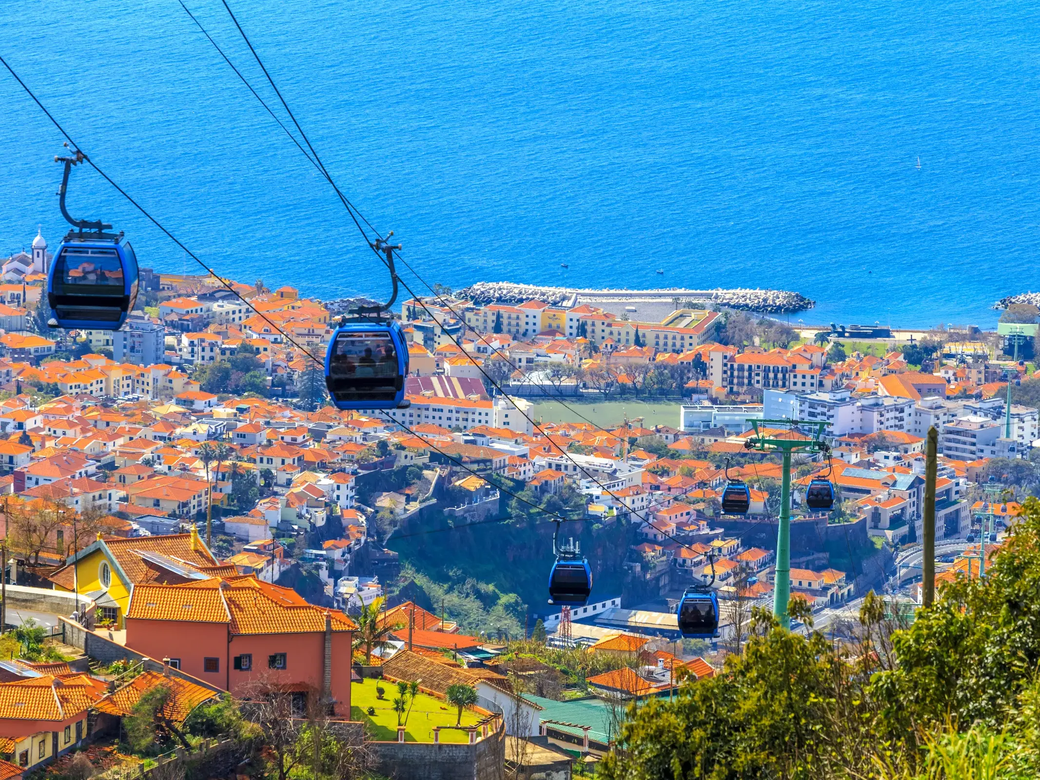 Mit der Seilbahn über die orangefarbenen Dächer von Funchal hinauf nach Monte mit Aussicht auf den Atlantik.