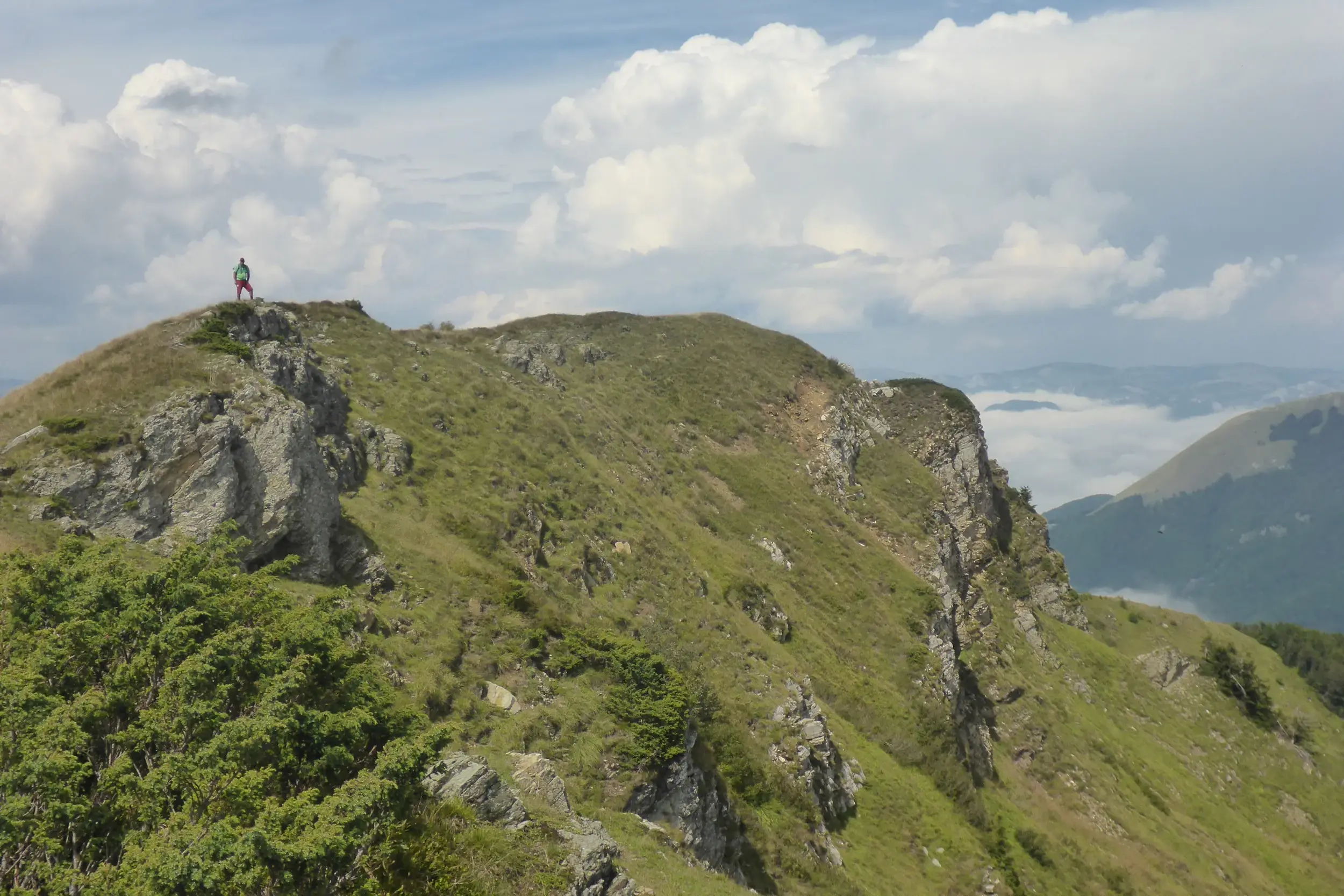 Ein Wanderer steht auf dem felsigen Gipfel des Crvena Greda und genießt den Panoramablick über die Karstlandschaft des Durmitor.