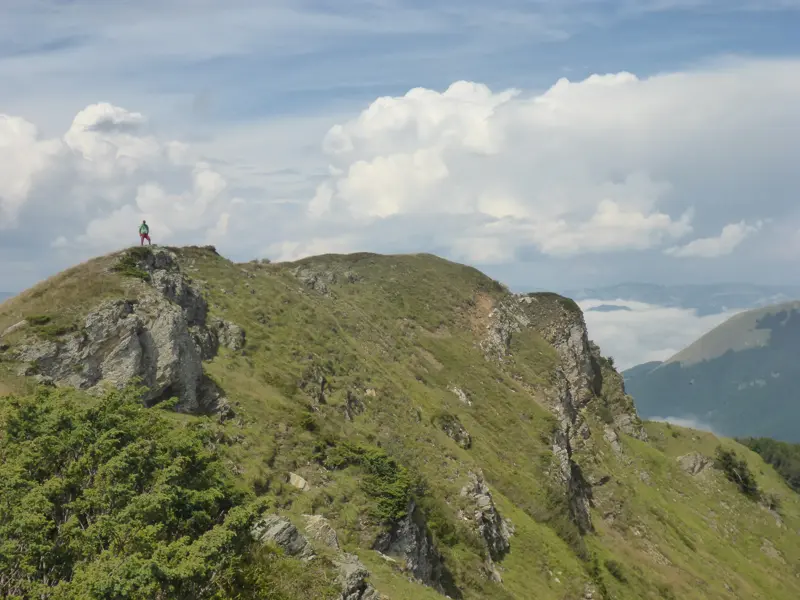 Ein Wanderer steht auf dem felsigen Gipfel des Crvena Greda und genießt den Panoramablick über die Karstlandschaft des Durmitor.