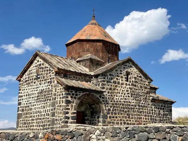 Historische Gergeti-Dreifaltigkeitskirche aus Stein bei Stepantsminda in Georgien vor blauem Himmel im Kaukasus.
