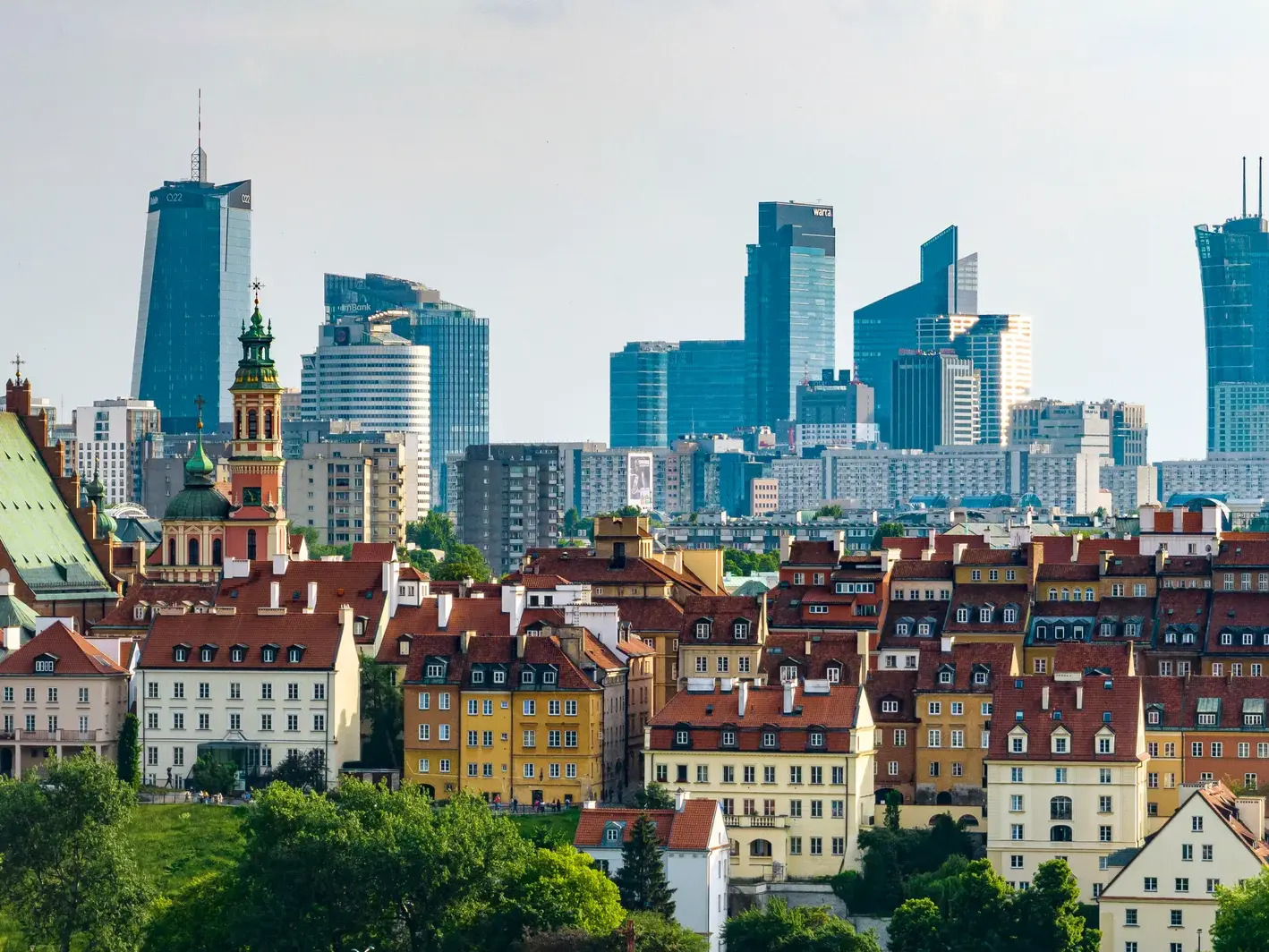 Historische Gebäude der Altstadt Warschaus vor der beeindruckenden Skyline mit modernen Wolkenkratzern der polnischen Hauptstadt.