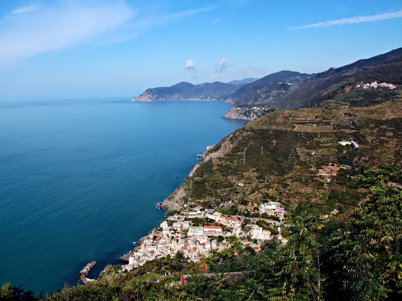 Panoramablick von einem Wanderweg auf das Küstendorf Riomaggiore, die terrassierten Weinberge und die ligurische Küste.