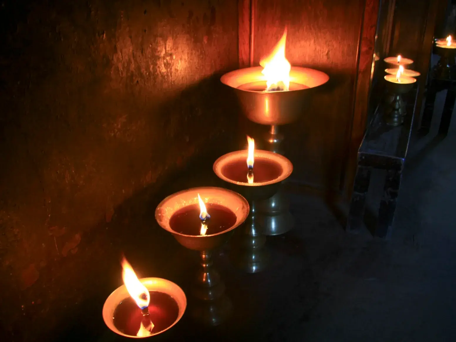 Spirituelle Butterlampen brennen in Metallschalen in einem Kloster in der Khumbu-Region in Nepal und spenden warmes Licht.