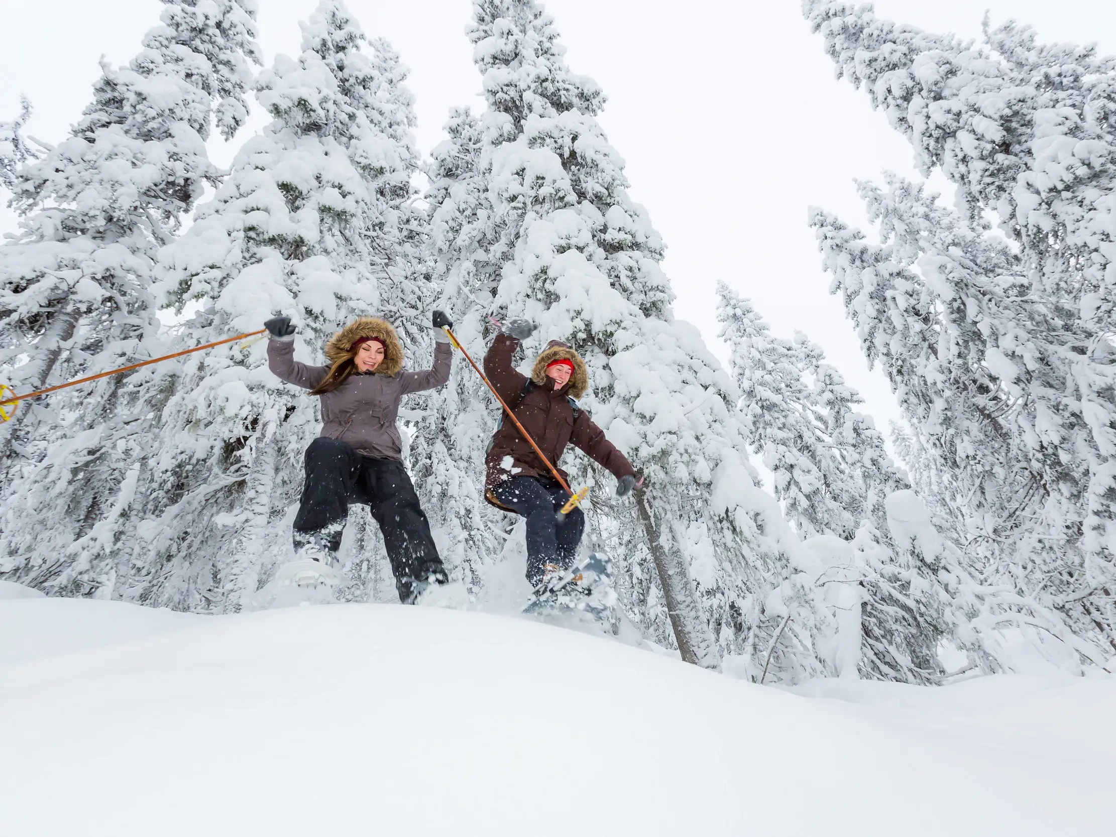 Junge Frau und Mann jubeln auf ihrer Tour durch die tief verschneite Winterlandschaft Finnlands.