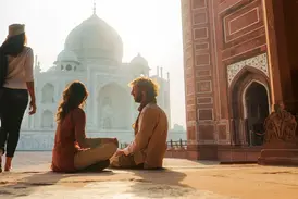 Junge Reisende entspannen im warmen Morgenlicht auf dem Vorplatz des berühmten Taj Mahal Mausoleums in Agra, Indien.