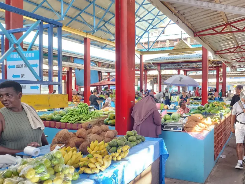 Buntes Treiben auf dem Markt in Victoria, Mahé: Einheimische bieten exotische Früchte an, während Reisende vorbeischlendern.
