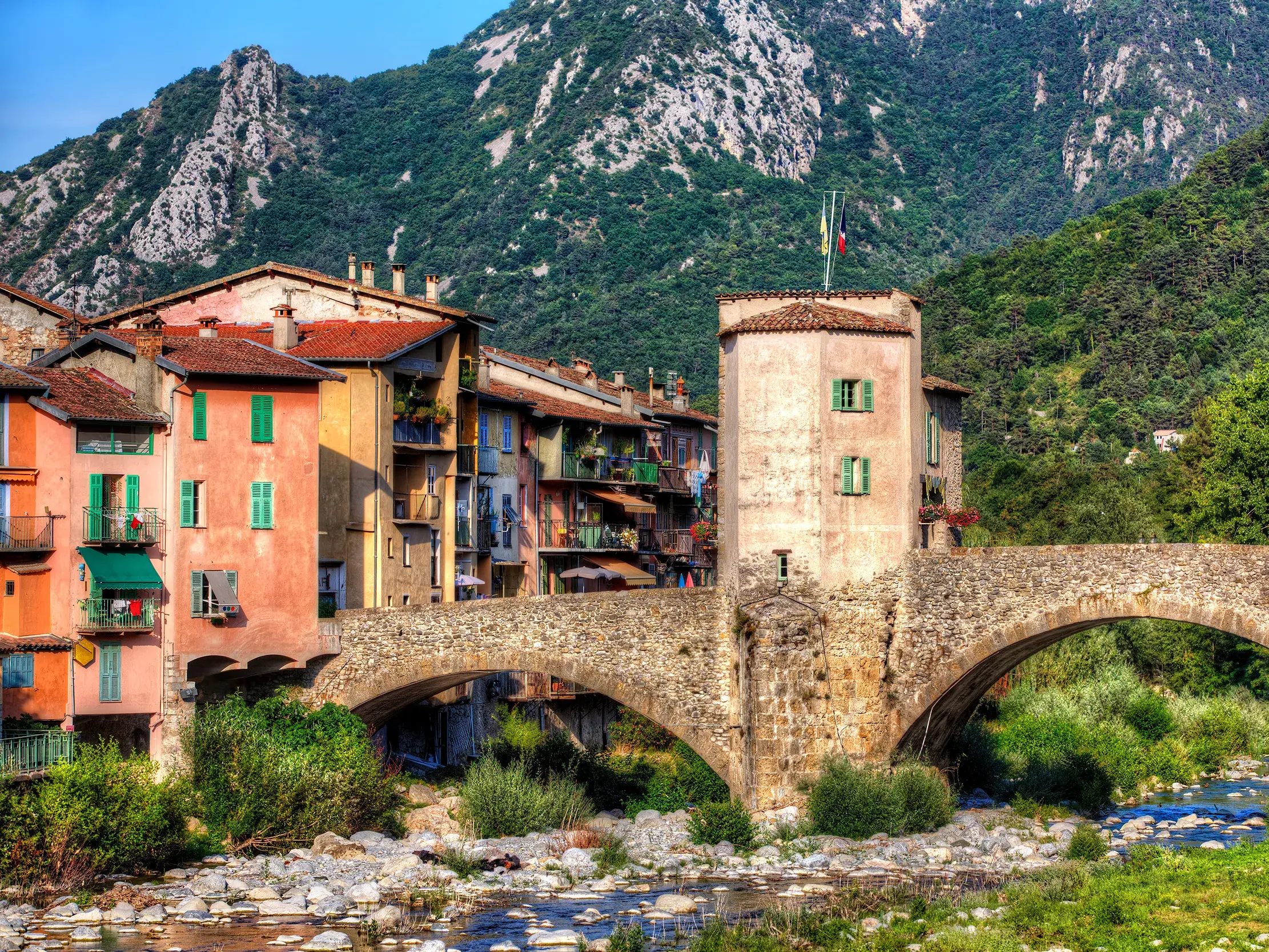 Die malerische Ponte Vecchio Bogenbrücke in Dolceacqua spannt sich über den Nervia-Fluss vor bunten Häusern und grünen Bergen.
