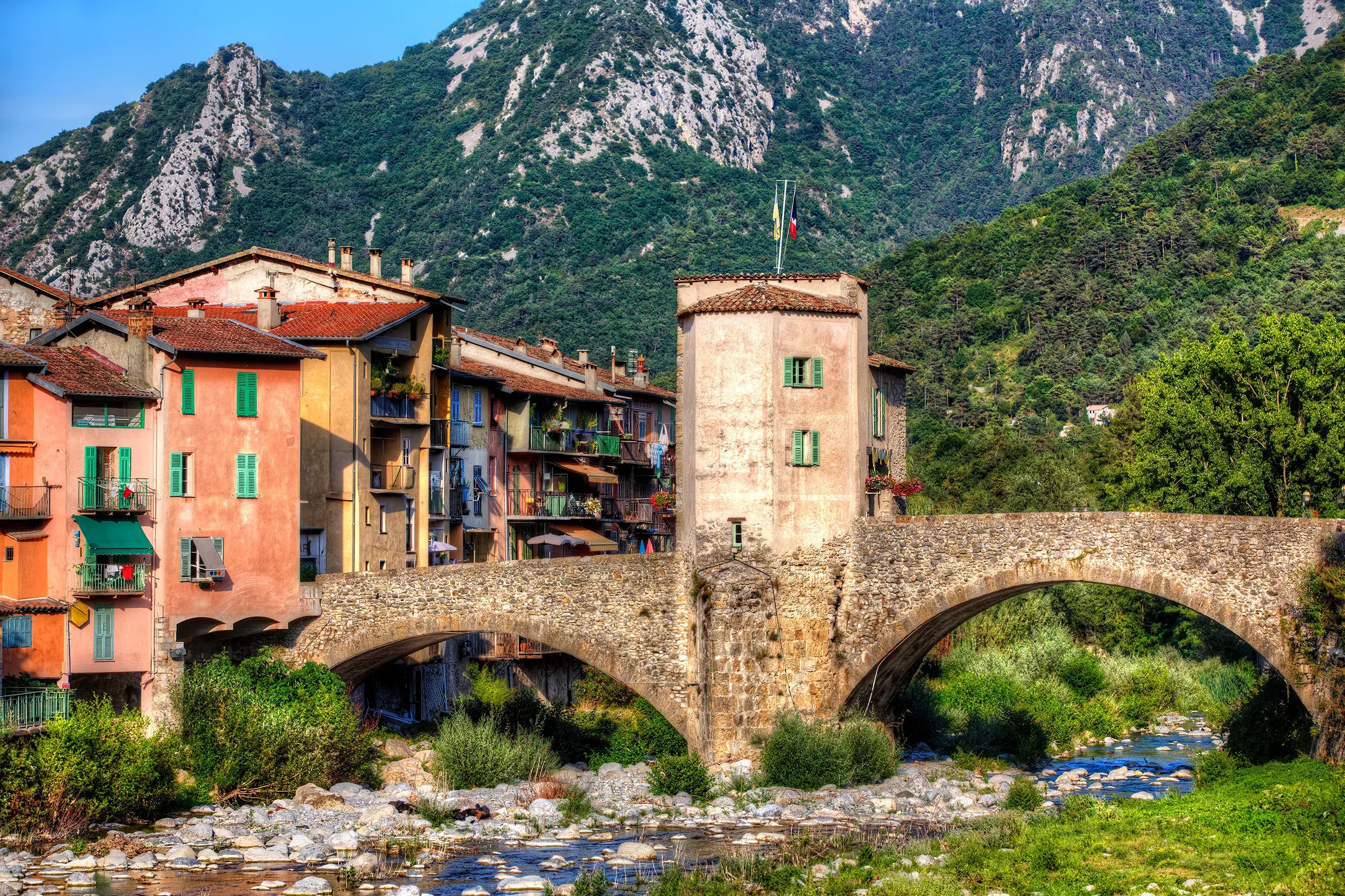 Die malerische Ponte Vecchio Bogenbrücke in Dolceacqua spannt sich über den Nervia-Fluss vor bunten Häusern und grünen Bergen.