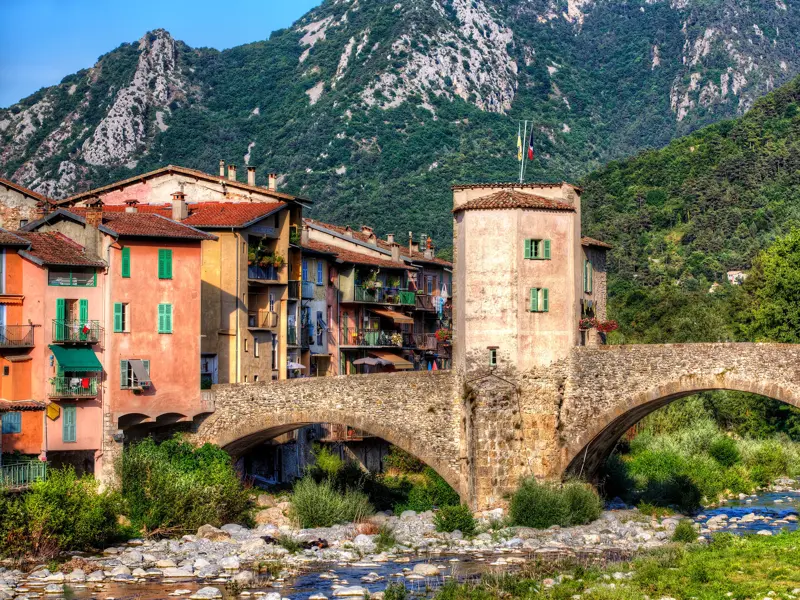 Die malerische Ponte Vecchio Bogenbrücke in Dolceacqua spannt sich über den Nervia-Fluss vor bunten Häusern und grünen Bergen.