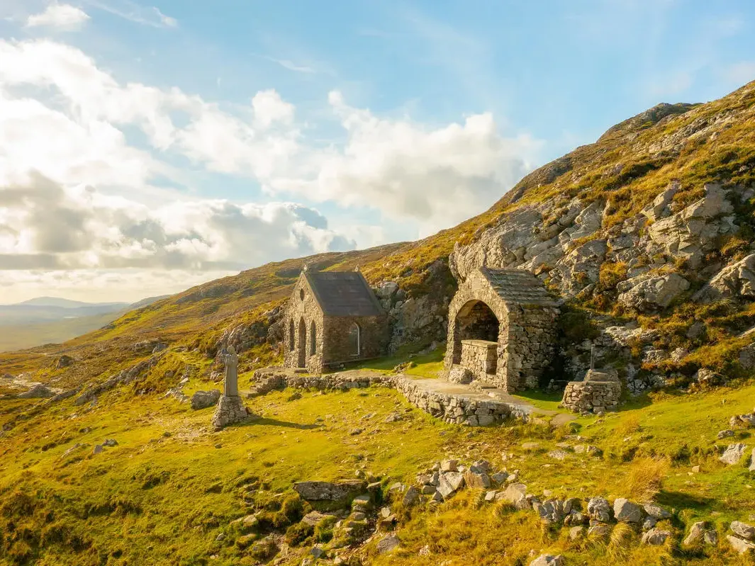 Die kleine St. Patrick Kapelle und ein Steinschrein am Maumeen-Pass in der wilden Bergwelt der Maumturks in Connemara.