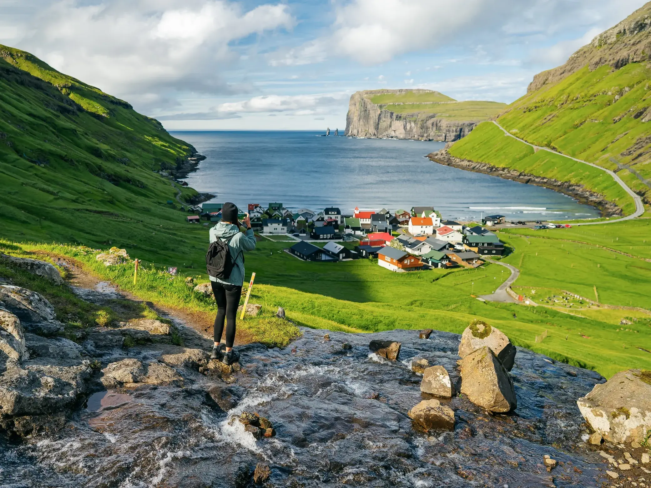 Wanderin fotografiert das Dorf Tjørnuvík auf den Färöer-Inseln mit Blick auf die Felsen Risin und Kellingin.