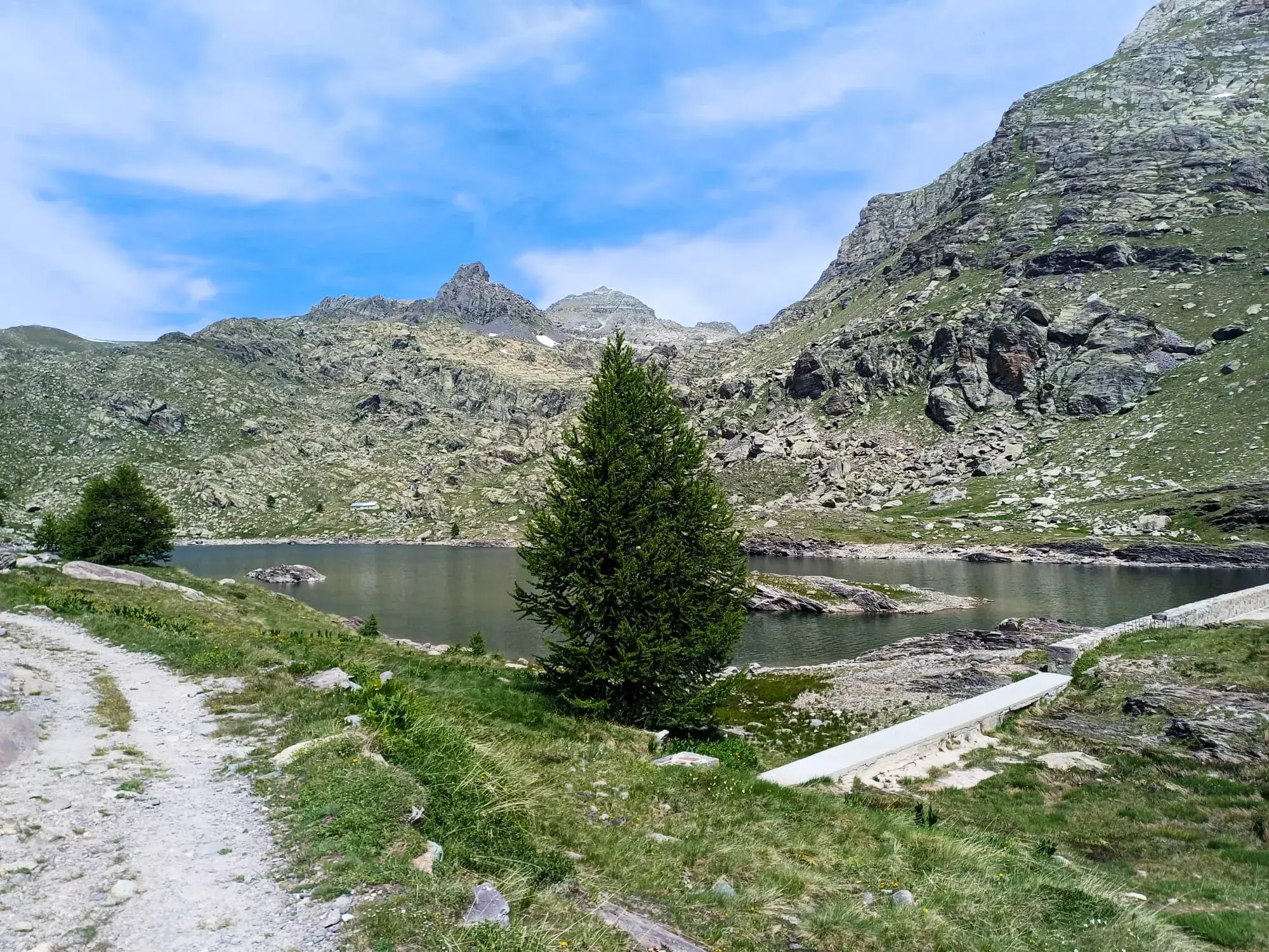 Wanderweg entlang eines idyllischen Bergsees, umgeben von den schroffen Gipfeln der Seealpen bei Nizza an einem Sommertag.