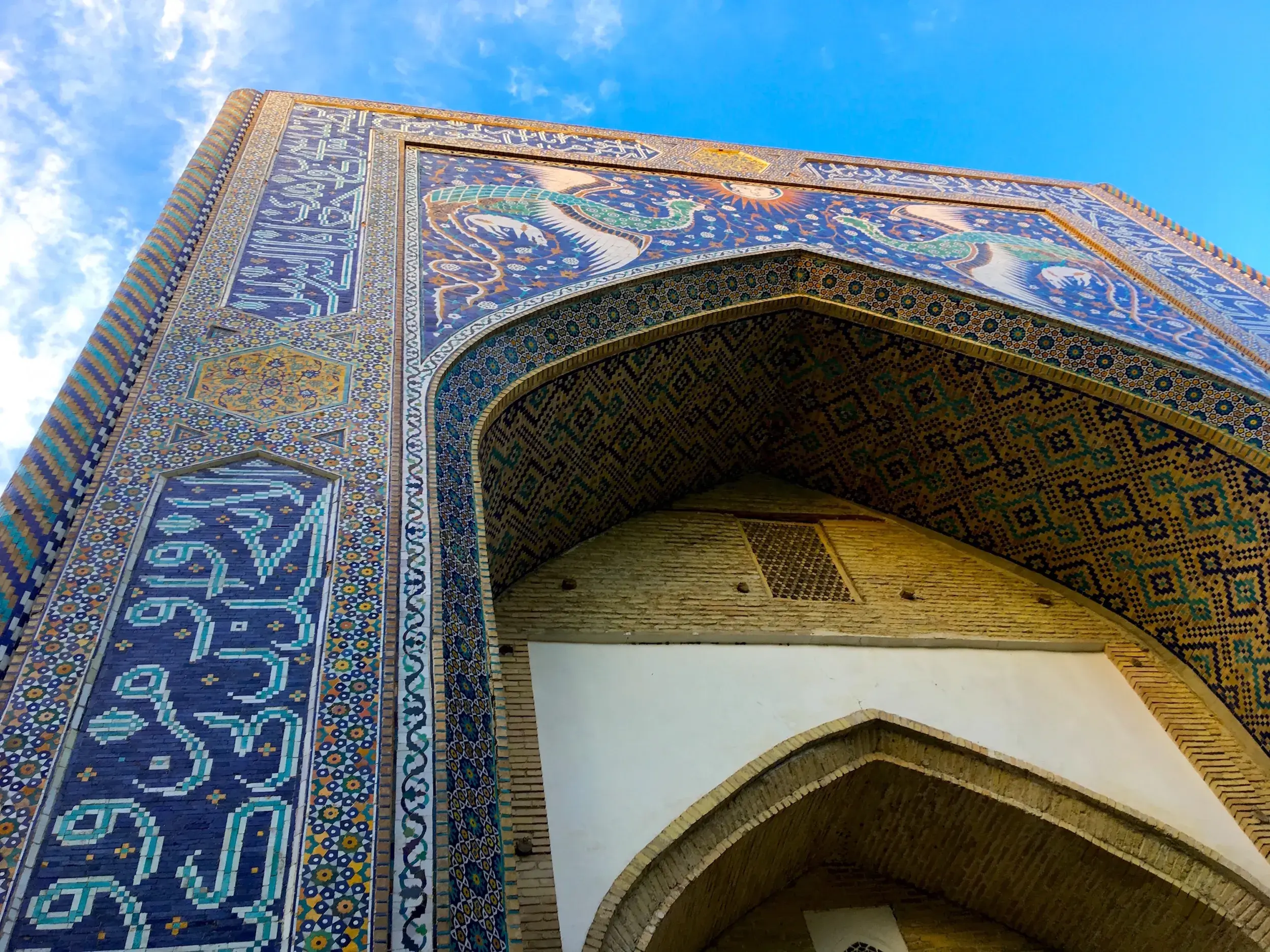 Froschperspektive auf das prachtvolle Mosaik-Portal der Nadir Divan-Begi Medrese in Buchara mit Kalligrafie und Simurgh-Vögeln.