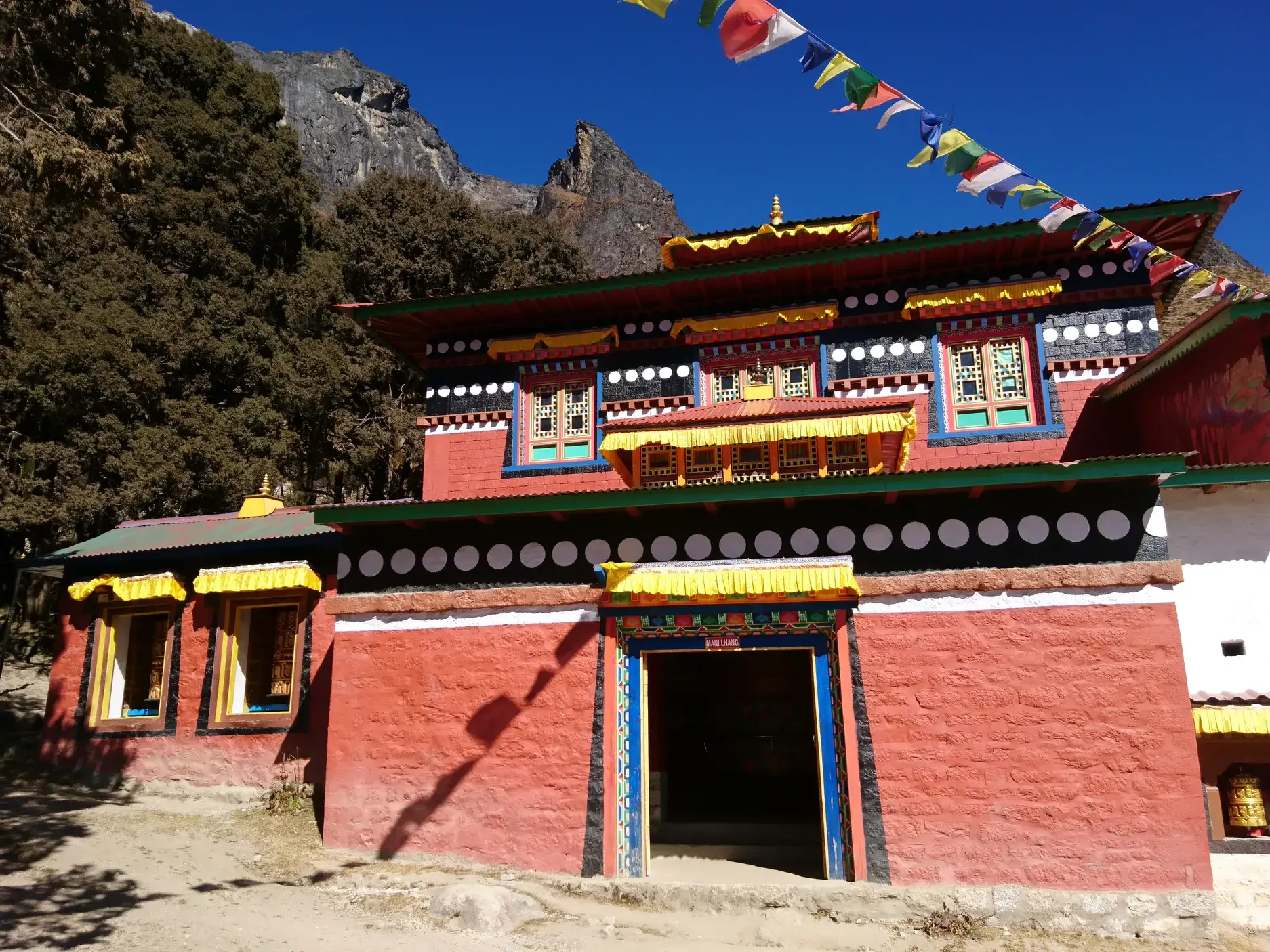 Das rote Kloster von Thame mit bunten Gebetsfahnen vor der Kulisse der Berge während einer Trekkingreise in Nepal.