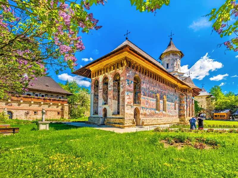 Farbenprächtige Außenfresken des UNESCO-Welterbes Kloster Voronet in der rumänischen Region Südbukowina unter blauem Himmel.