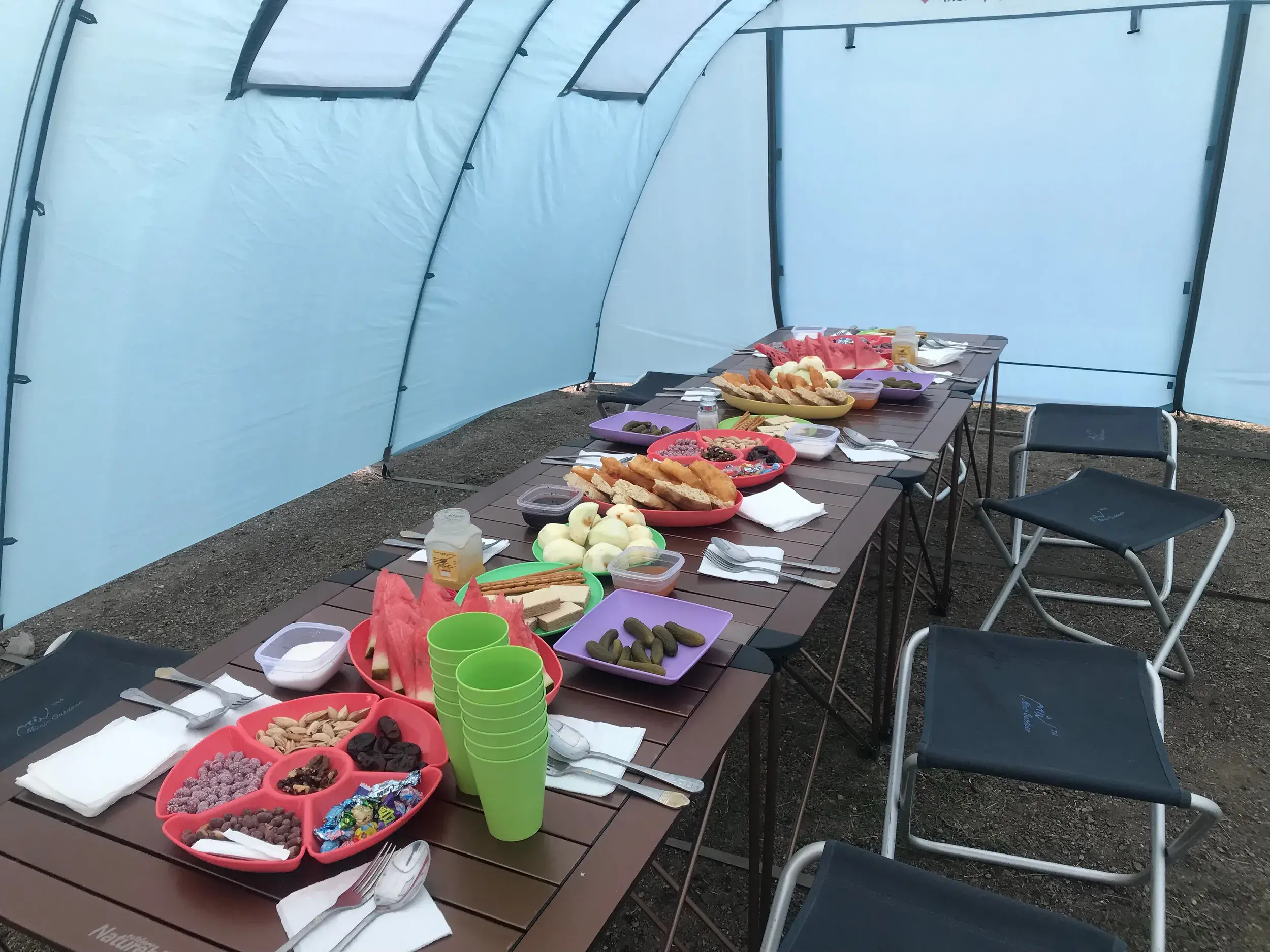 Reich gedeckter Esstisch im Gemeinschaftszelt mit lokalen Speisen wie Obst und Brot während des Trekkings in Tadschikistan.